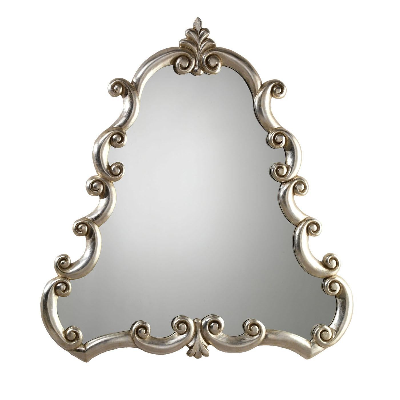 Superb example of Florentine Renaissance style, this solid wooden wall mirror boasts rich decorative details resulting from a patient and minute manual carving process. Silver-leaf adheres to the frame for enriching its triumph of curls with a