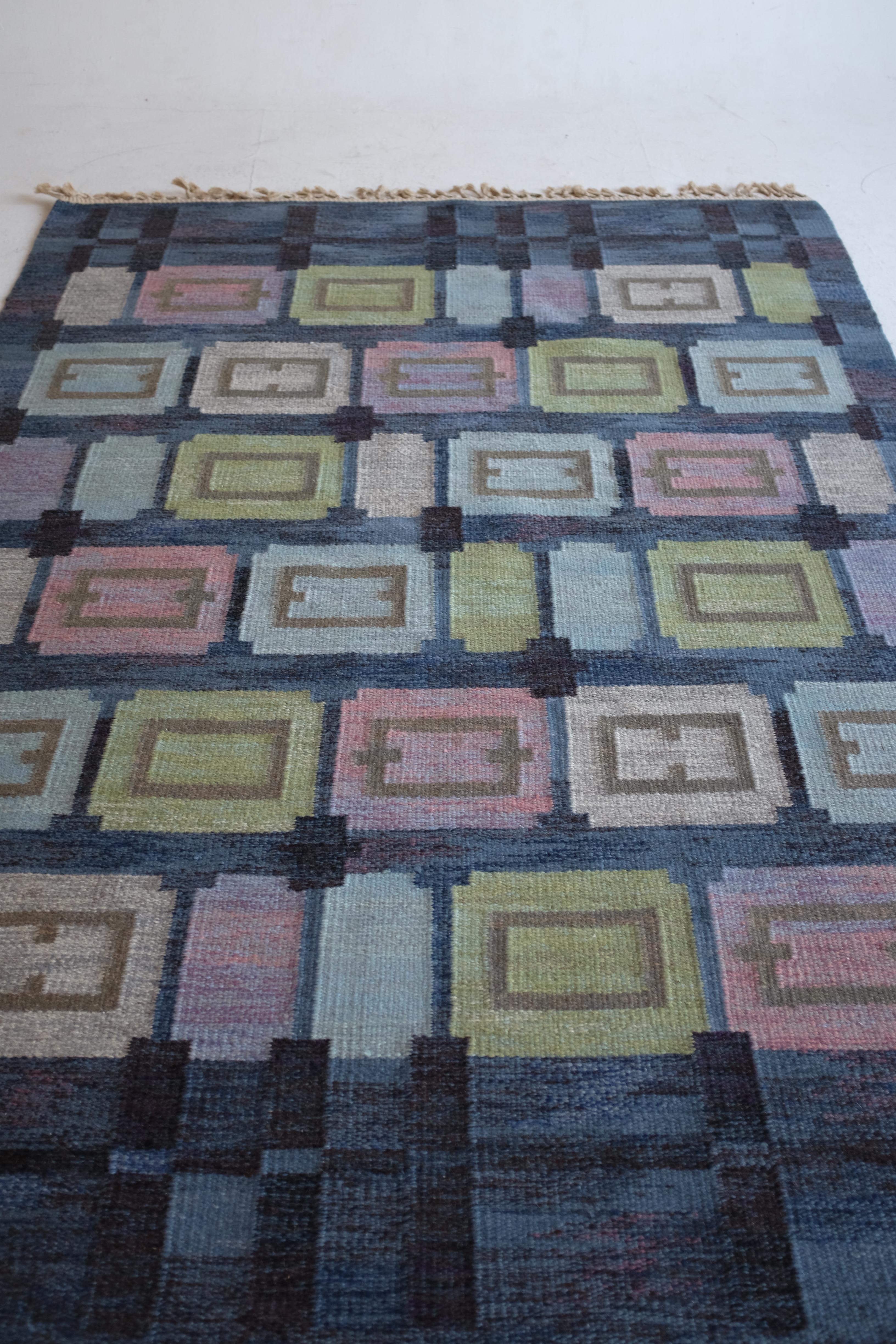 Atemberaubender schwedischer Mid-Century-Teppich namens Spise hall von Judith Johansson. Es wurde 1961 entworfen und zeigt einen blauen Hintergrund mit einem Kaleidoskop-Muster in Grün-, Rosa- und Lila-Tönen. Judith Johansson war eine schwedische