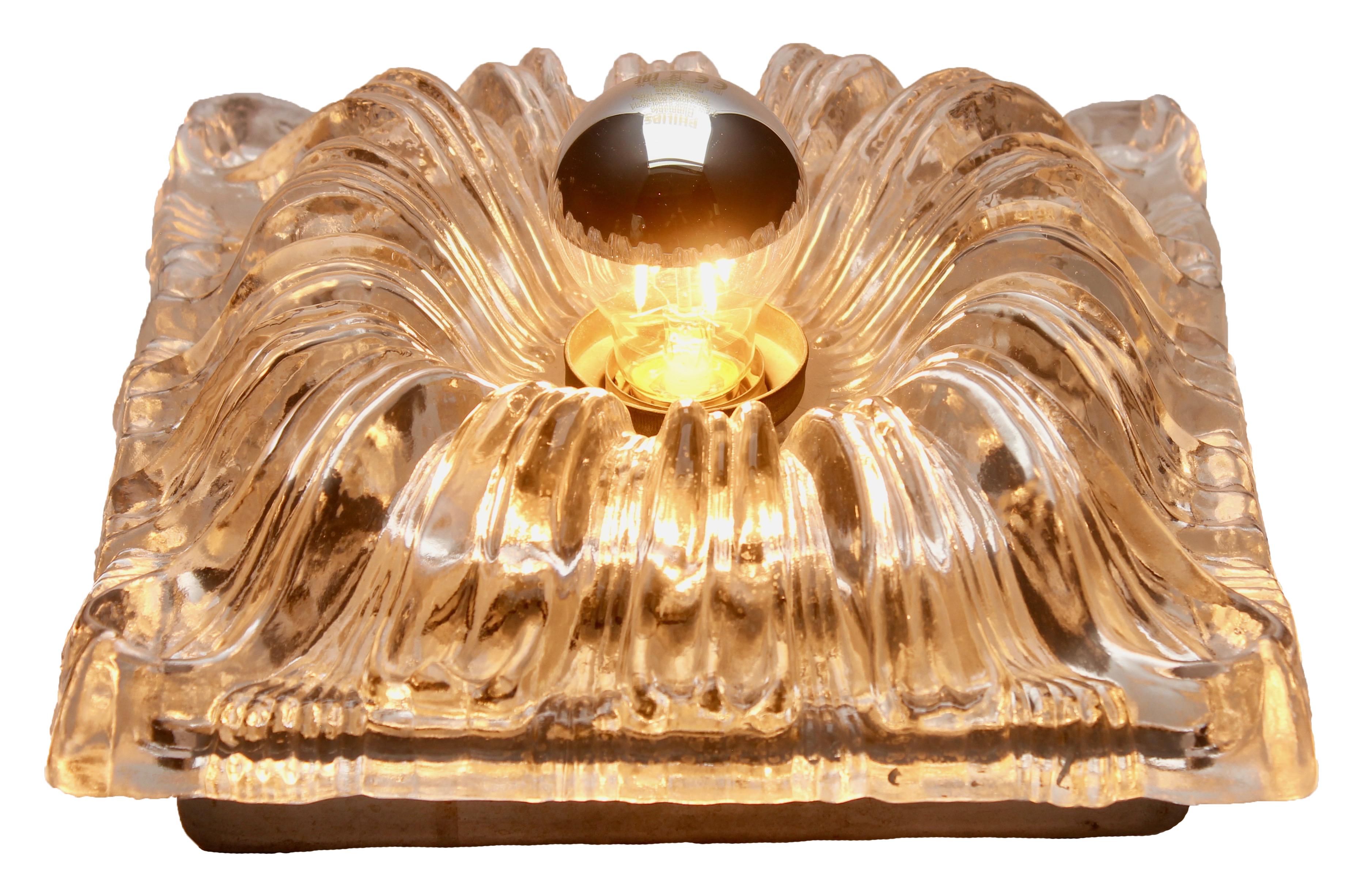 This dramatic and eye-catching 3-D sculptural wall (or ceiling) lamp was designed specifically for use with a mirrored bulb (still available) which reflects the light through the deeply sculpted waves of glass to give an attractive warm