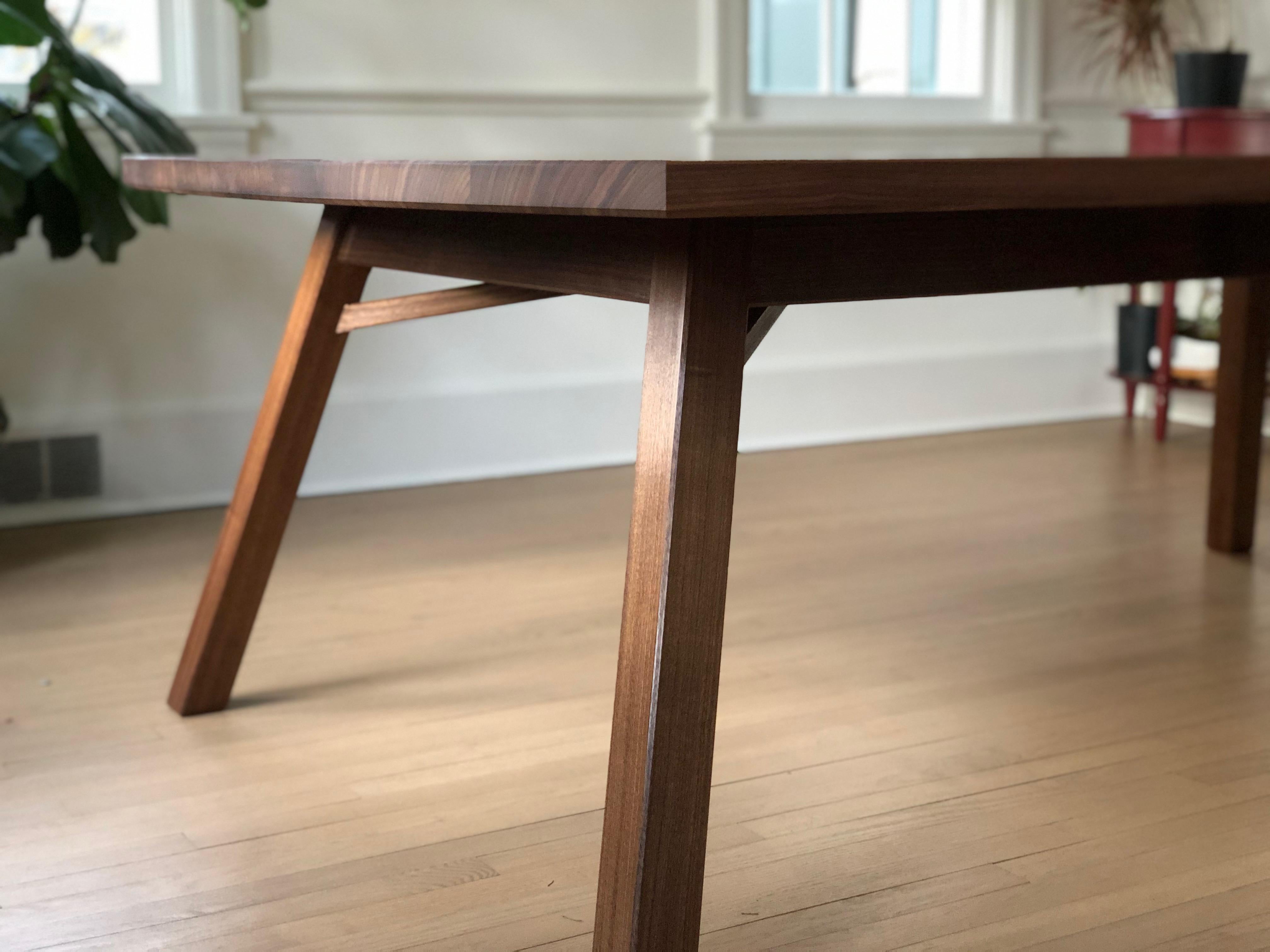 This dining table takes inspiration from the traditional Japanese bell tower in its use of a splayed leg structure that appears to feature square section legs. Upon closer inspection one realizes that the legs are a parallelogram shape, unique to