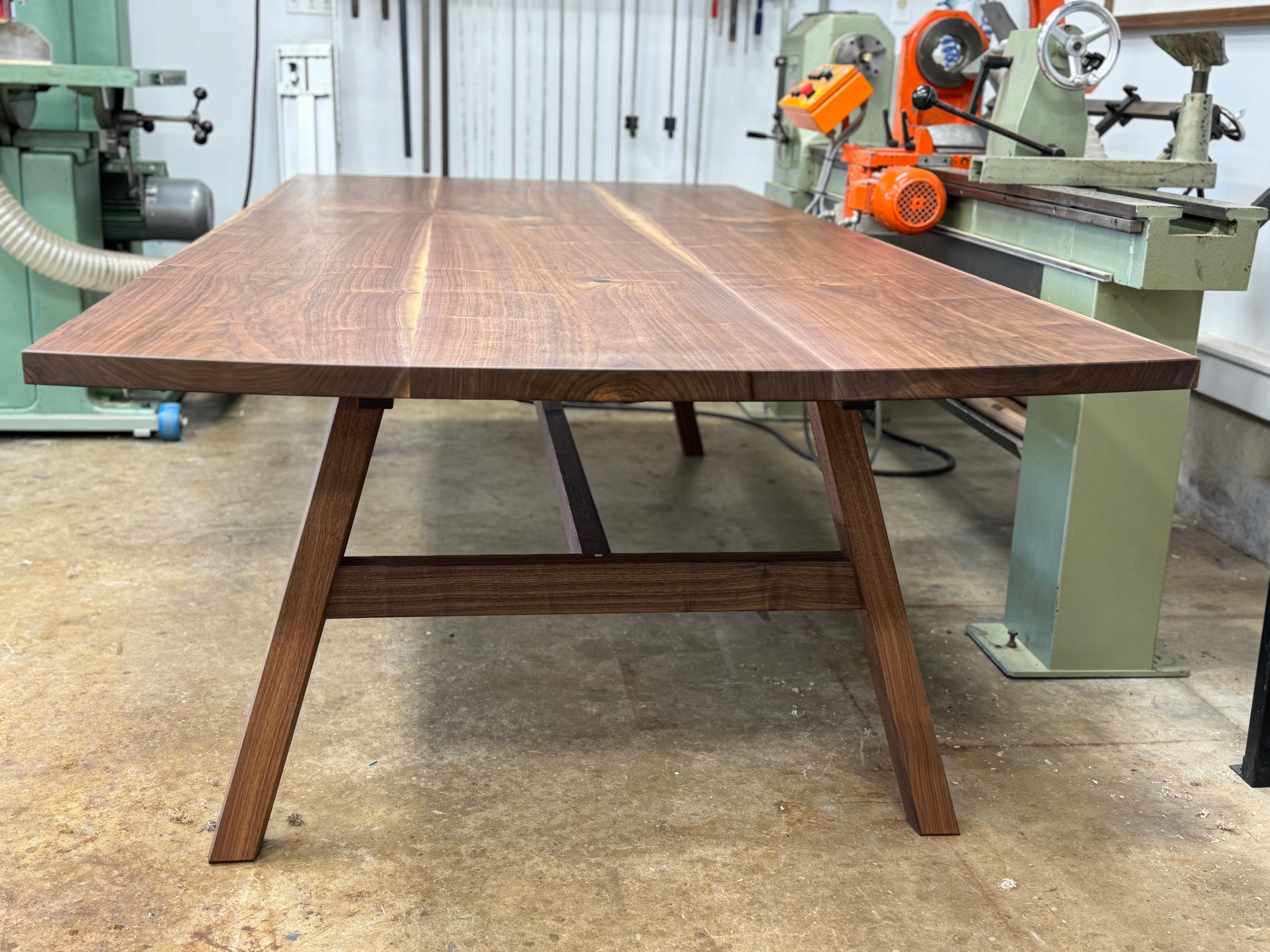Cette table de salle à manger s'inspire du clocher japonais traditionnel par l'utilisation d'une structure à pieds évasés qui semble comporter des pieds de section carrée, dans ce cas arrondis sur leurs faces extérieures.  La structure des pieds