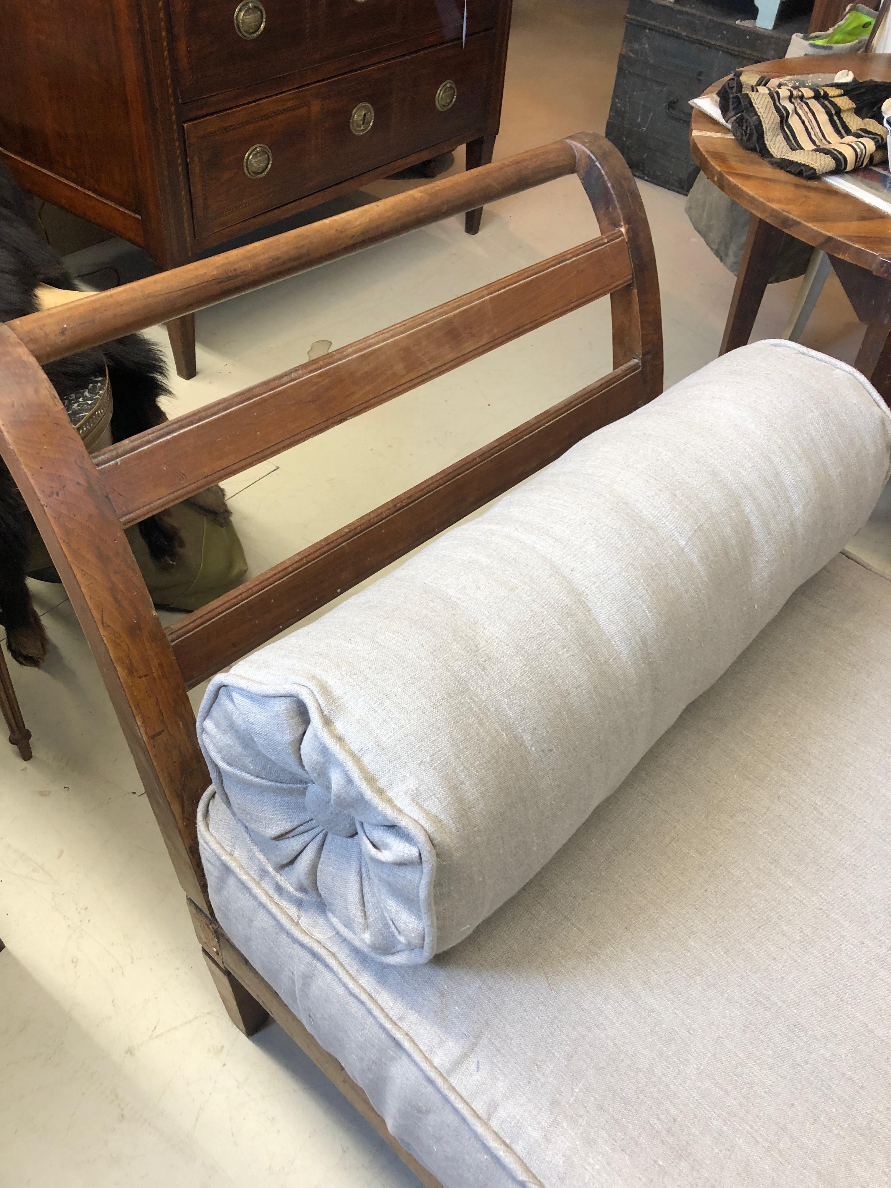 Handsome rustic wood French daybed newly upholstered in taupe linen with bolsters.