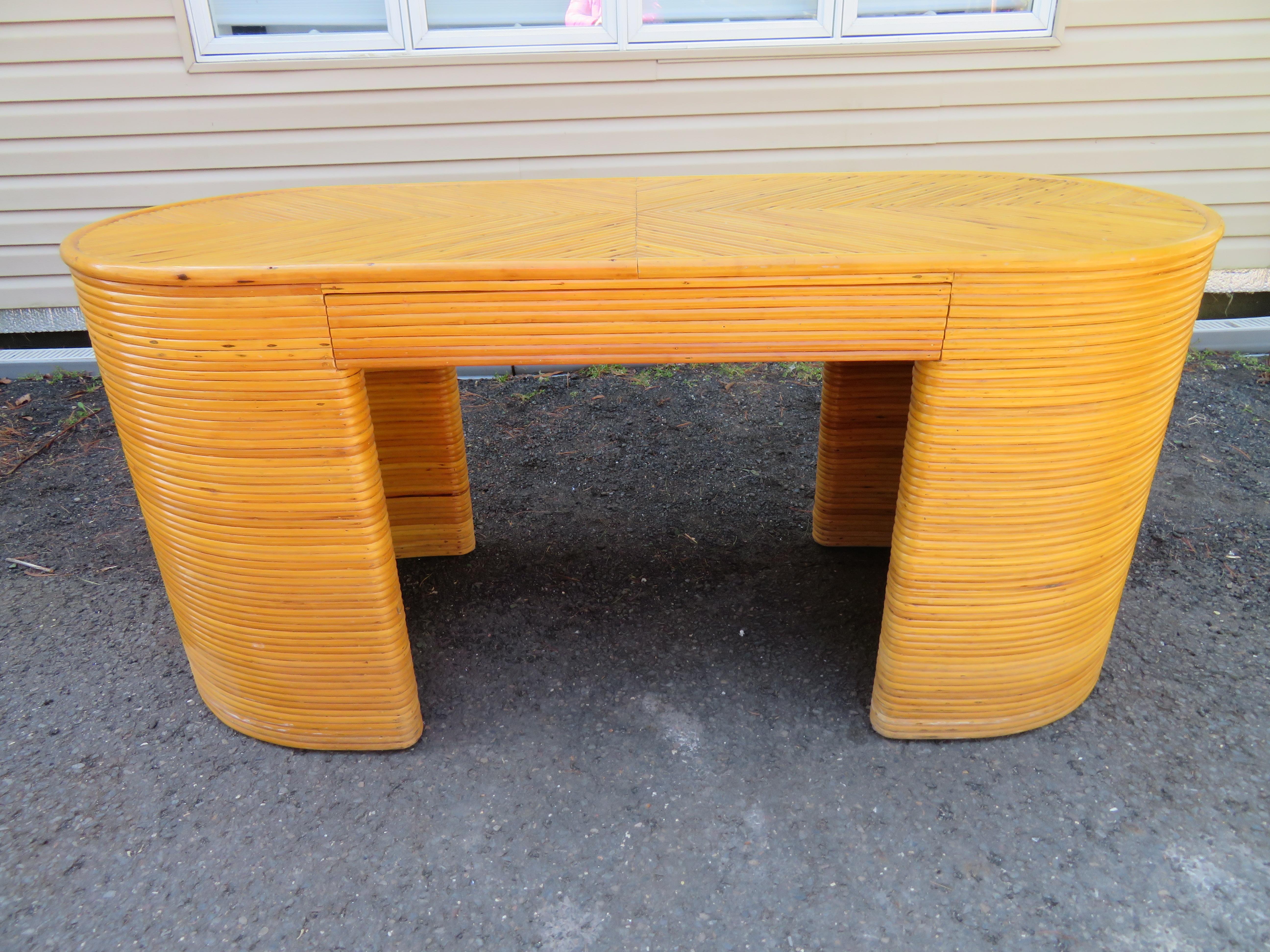 Splendid split reed bamboo desk with its original rattan chair. We just adore the unusual pill shape and hidden central drawer. The Asian style rattan chair is the original chair the owner purchased to go with the desk back in the '70s and looks