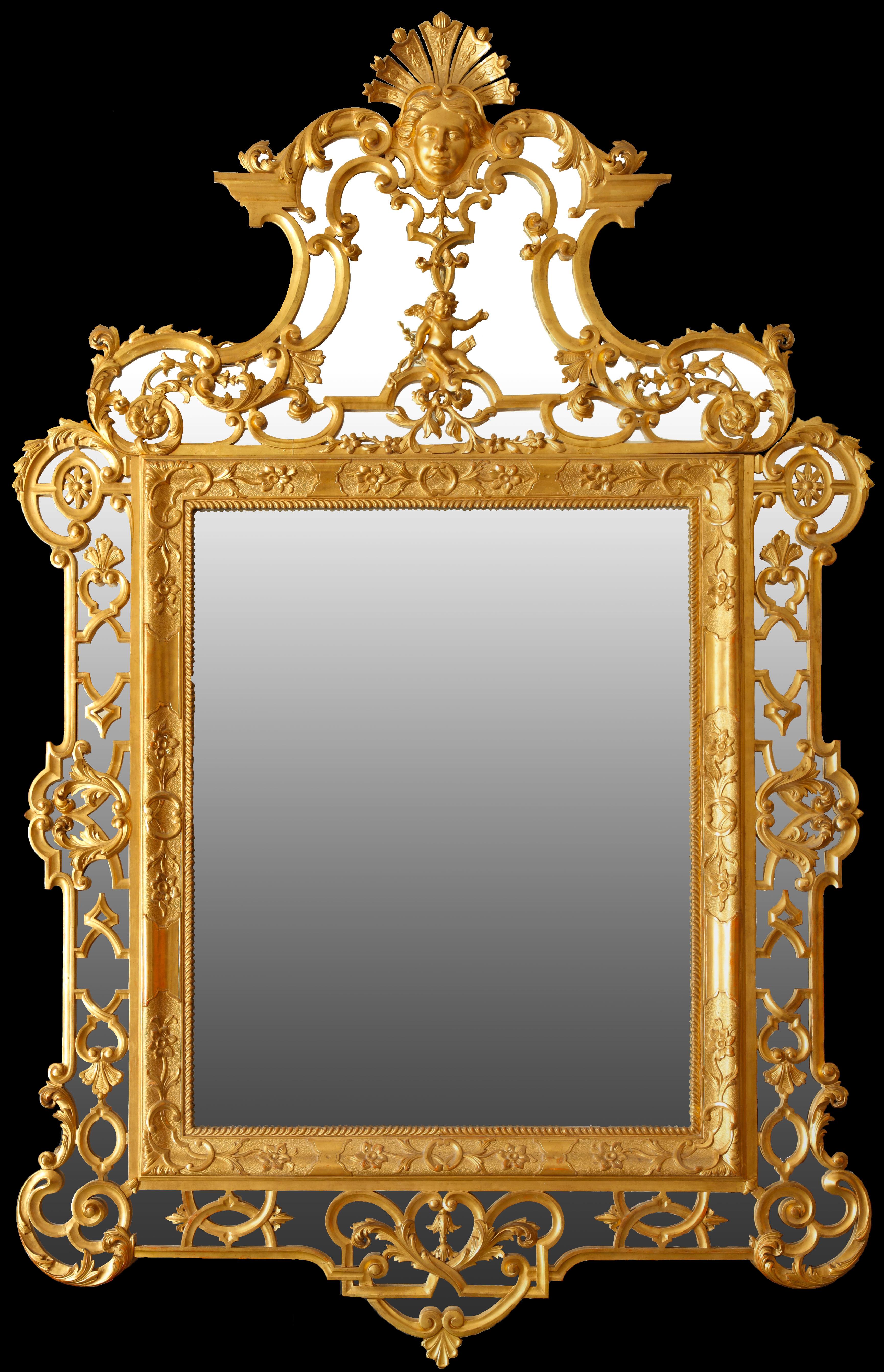 Un important miroir en bois doré sculpté avec un riche cadre magnifiquement décoré d'arabesques. Le sommet est richement orné d'un chérubin et surmonté d'un masque sur une coquille étalée. L'ensemble est abondamment sculpté de rinceaux, de fleurs et