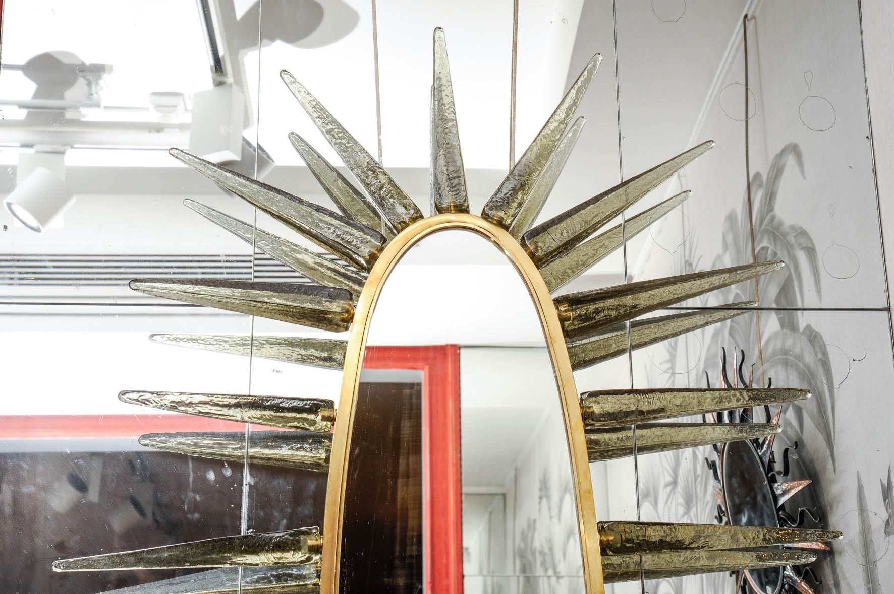 This mirror created by Studio Glustin is made of smoked mirror, brass and Murano glass for the pikes.