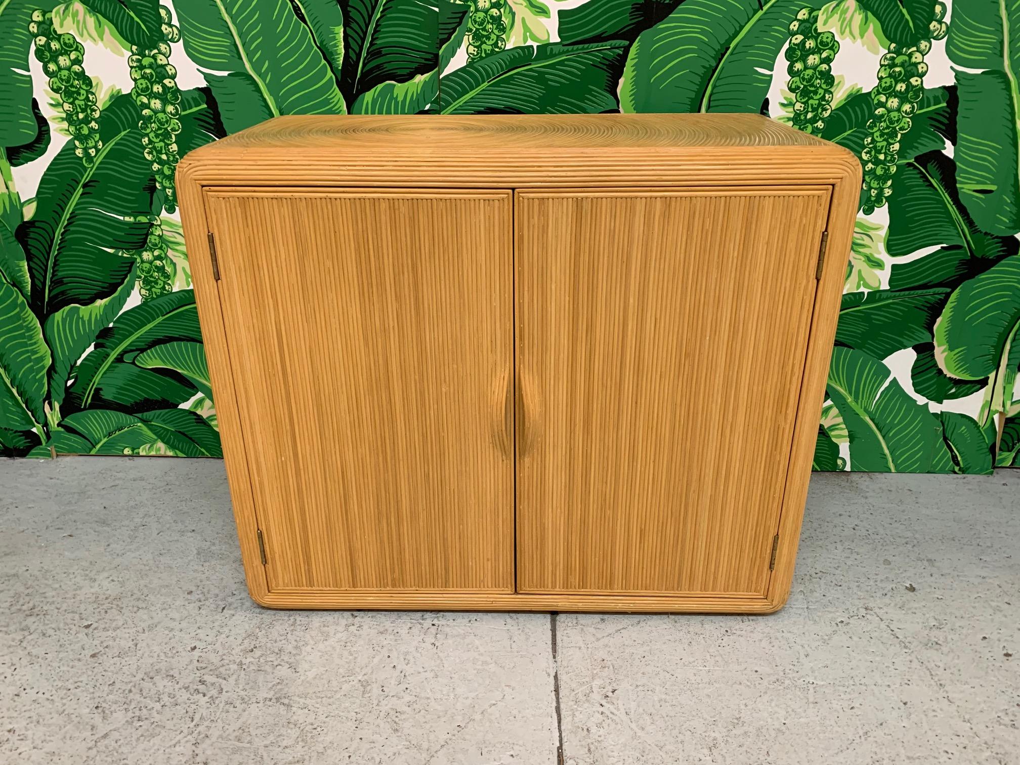 Double door storage cabinet features pencil reed design. Iconic sunburst design from intricate split reed rattan wrapped surfaces. Very good condition with minor imperfections consistent with age.