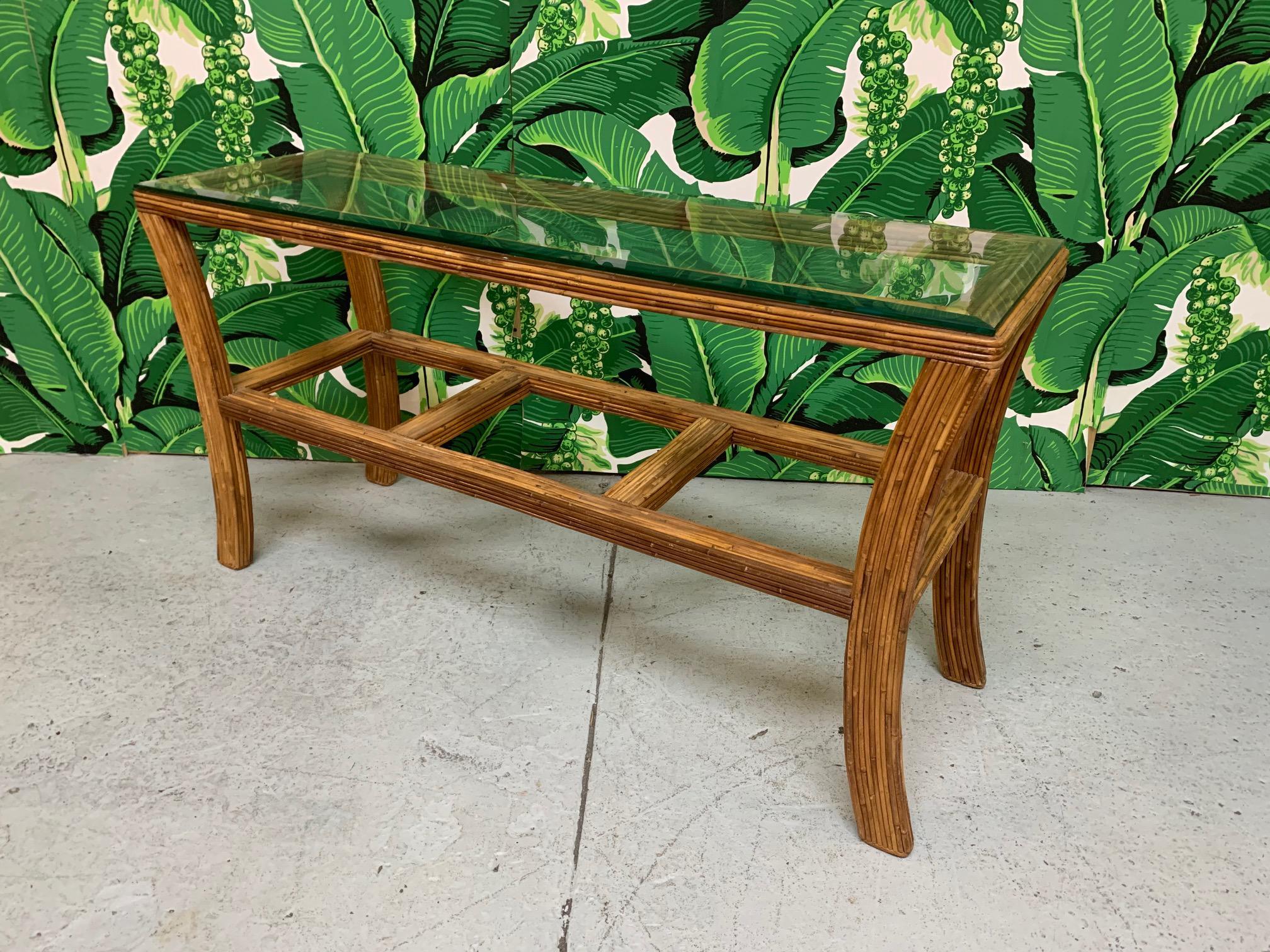 Mid-century rattan console table features split reed detailing and beveled glass top. Very good condition with only very minor imperfections consistent with age. 
 