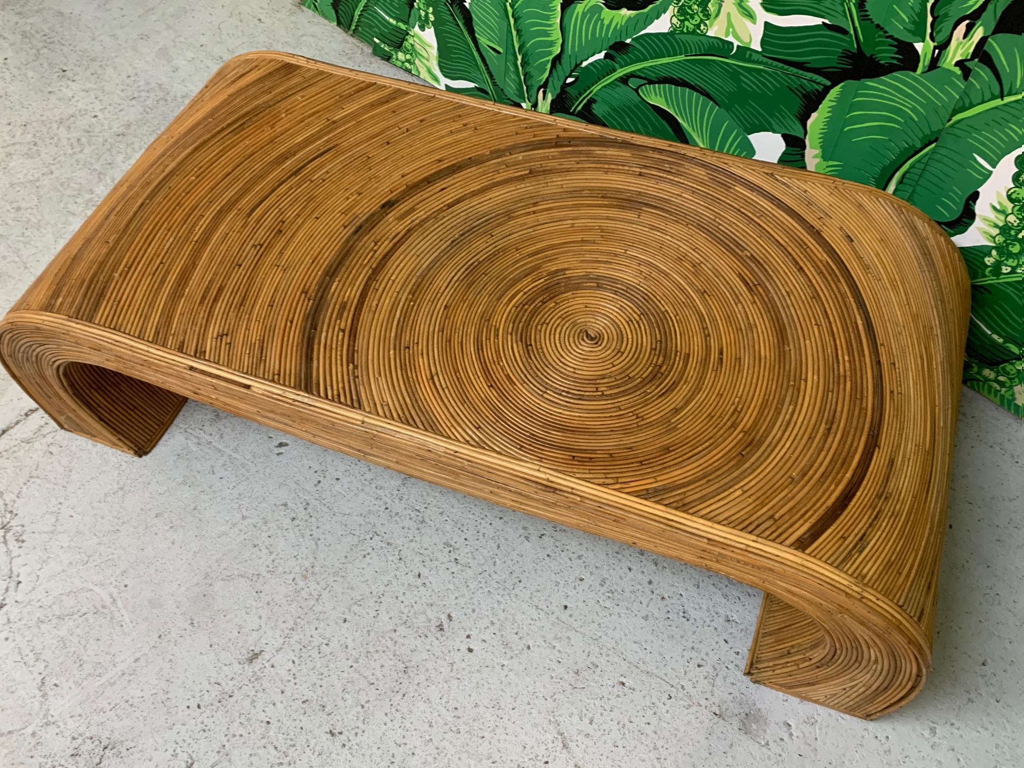 Waterfall coffee table features a complete veneer of pencil reed rattan in the style of Gabriella Crespi. Good vintage condition with minor imperfections consistent with age.