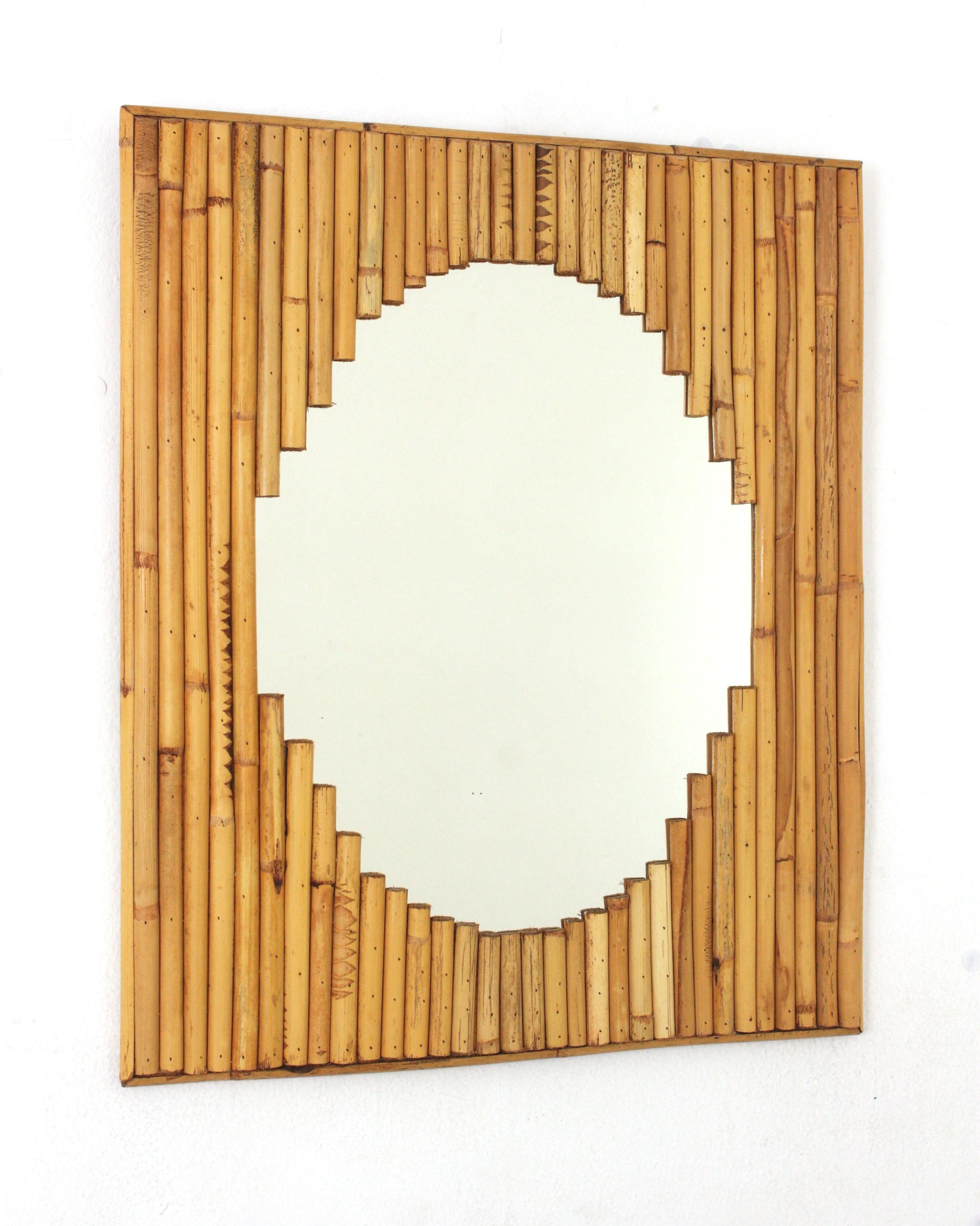 Midcentury Rectangular Wall Mirror, split reed, bamboo, rattan, Italy, 1960s.
This eyecatching rectangular shaped frame was handcrafted with bamboo cane and rattan and surrounds an oval mirror in scalloped disposition.
The frame is made of layers of