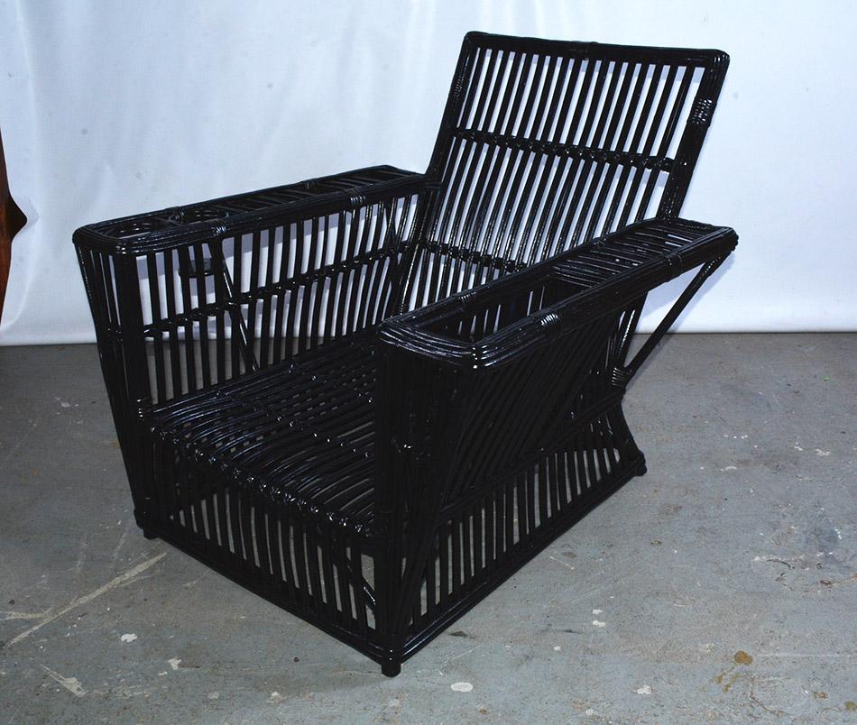 Antique American Art Deco split reed stick wicker arm chair with flat arms, magazine holder on one arm and drink holders on the other, painted black.
Reed is a rattan when it is sprouting. It is a durable fibrous material that has a similar look to