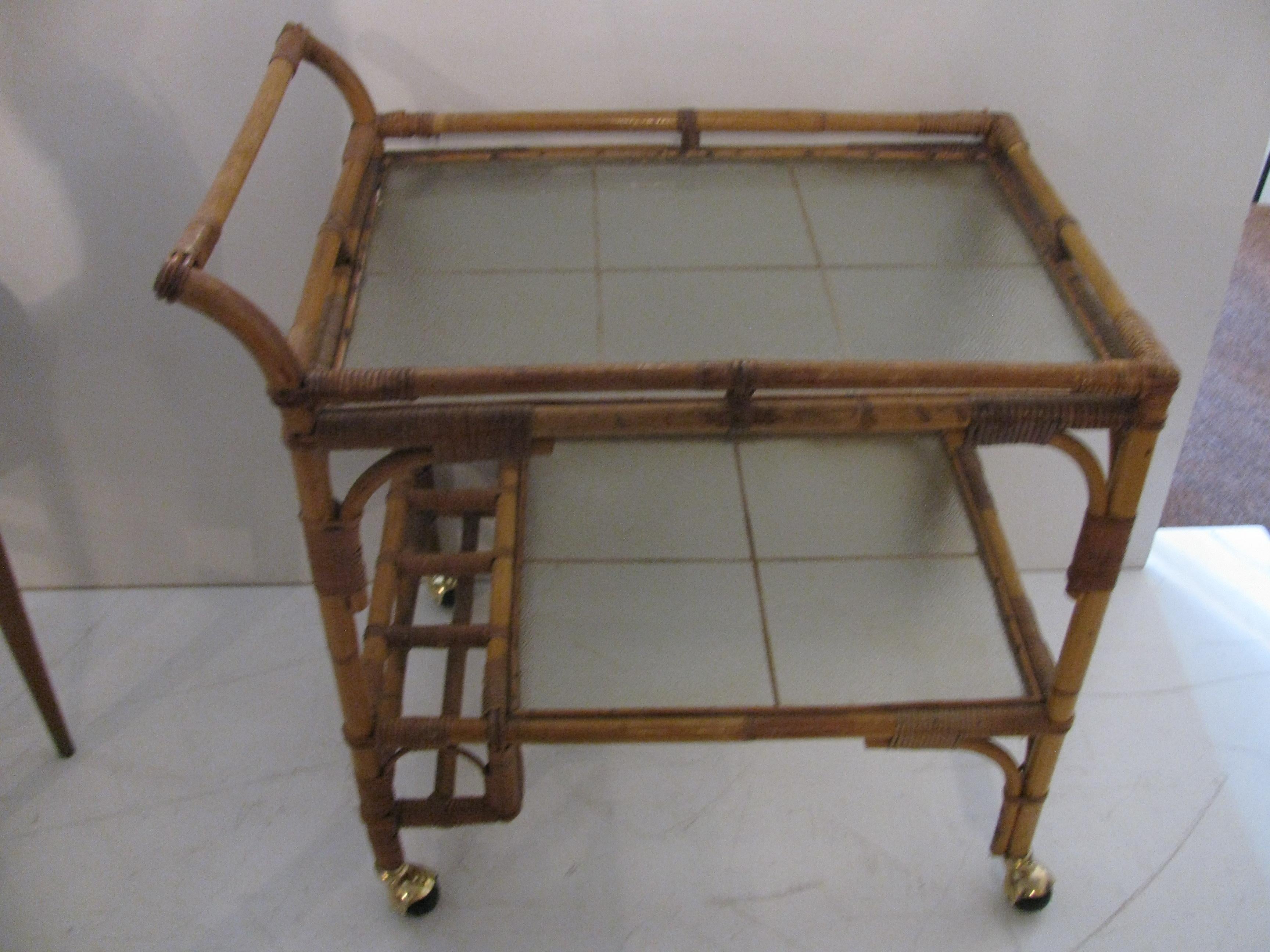 Rattan bar cart with frosted glass shelves. Bottle holder at the base on lower shelf. Measures: Shelf is 17 x 23.5in.