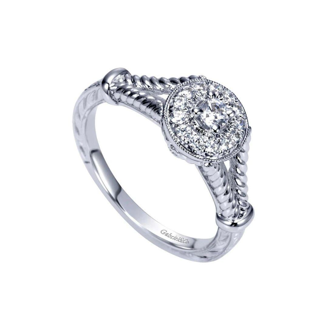 Diamond Halo Engagement Ring in 14k White Gold.﻿ Ring features vintage inspired rope design on a chic split shank and a beautiful diamond halo, surrounding the center diamond. Center diamond weighs 0.10 ct, H color, I1 clarity. Side diamonds are