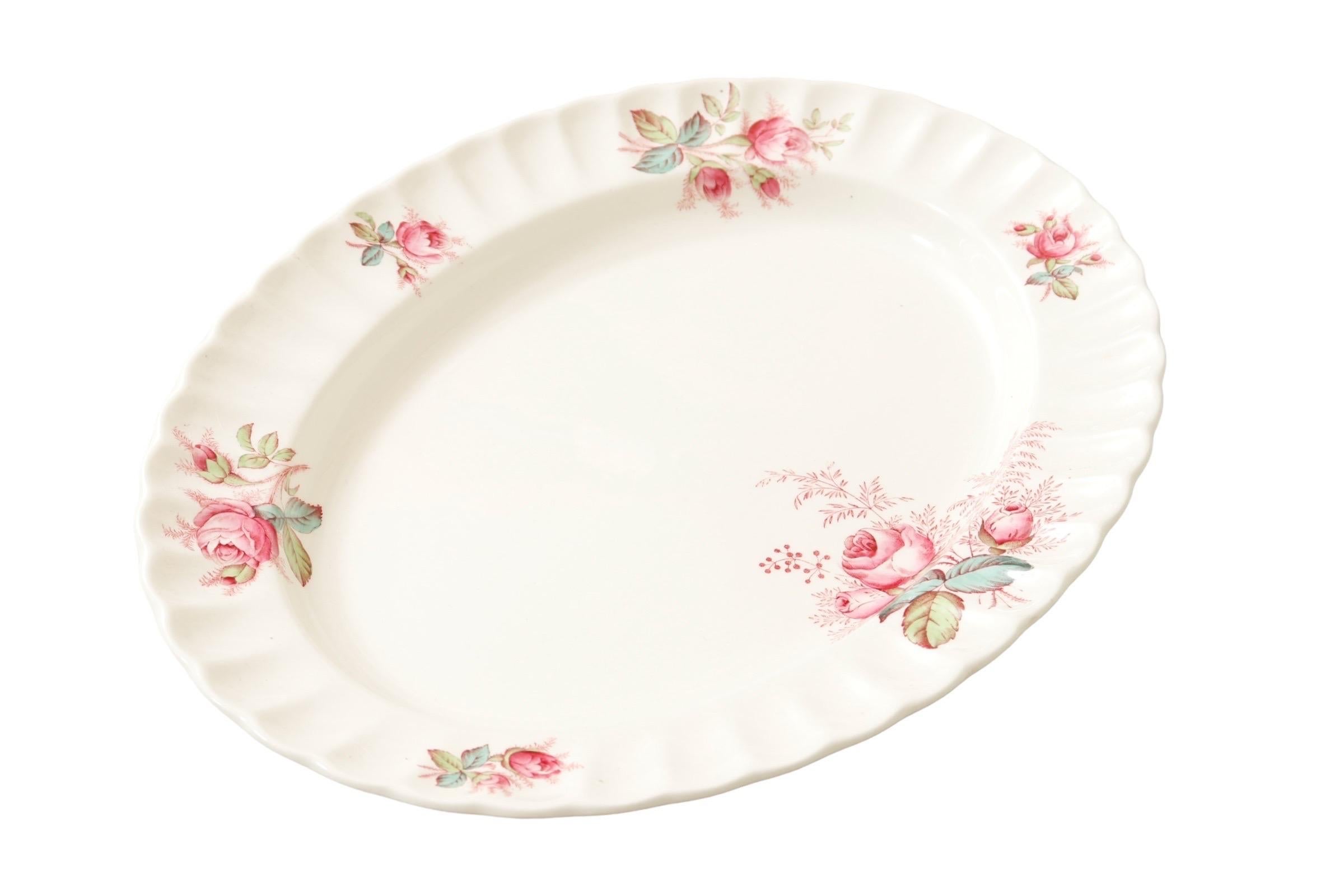 Plato ovalado blanco de cerámica de transferencia fabricado por Spode, con el motivo Dubarry, de 1946 a 1964. La fuente está decorada con rosas rosas en un borde festoneado, con un ramillete floral más grande en la parte inferior central. Marcado