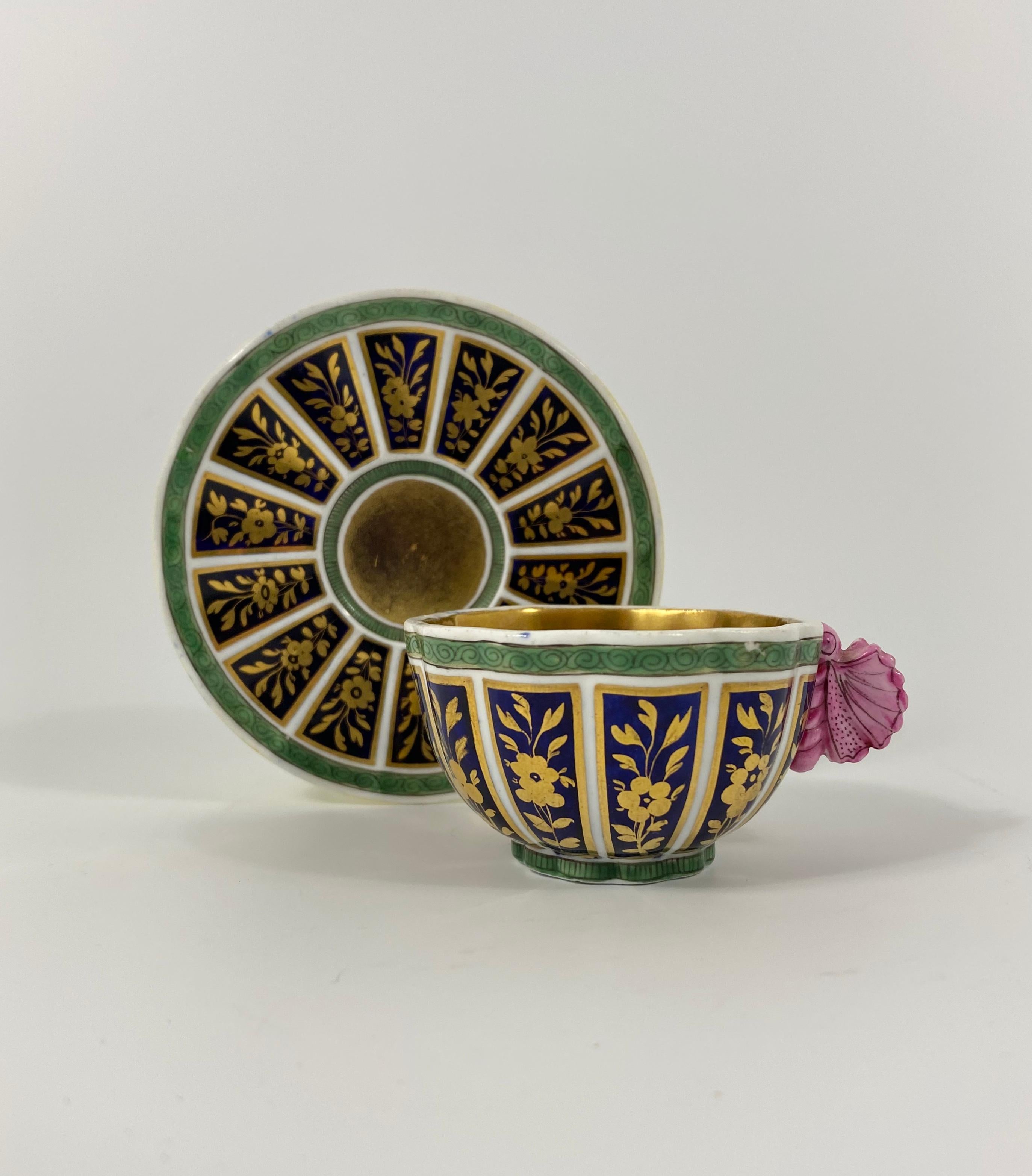 A rare Spode porcelain cup and saucer, circa 1815. Both items moulded, and painted with cobalt blue panels, containing gilded flowering plants, within green borders. The cup, gilded to the interior, and having a finely moulded pink butterfly