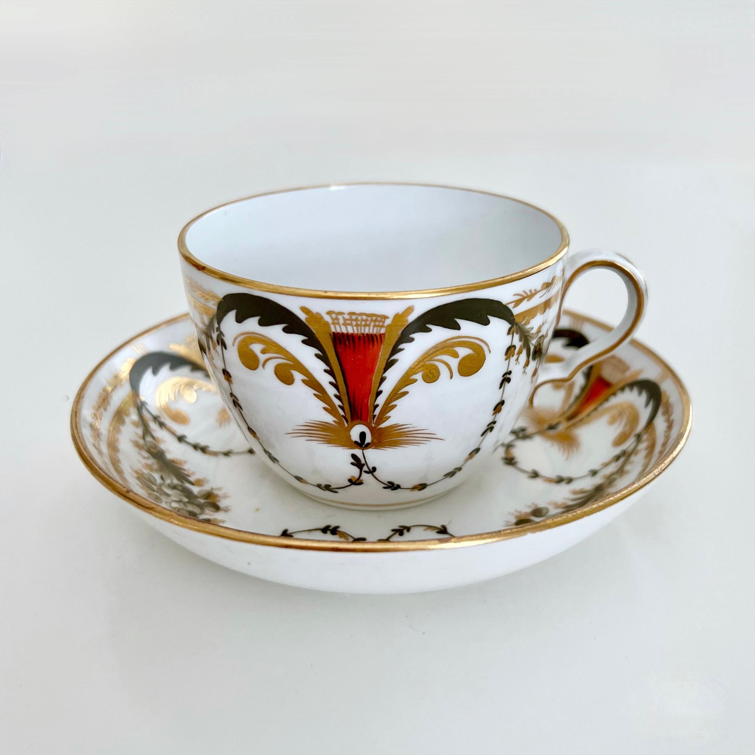 This is a beautiful teacup and saucer made by Spode around 1810. The set is decorated with a neoclassical pattern of red and black garlands. 

Josiah Spode was the great pioneer among the Georgian potters in England. Around the year 1800 he