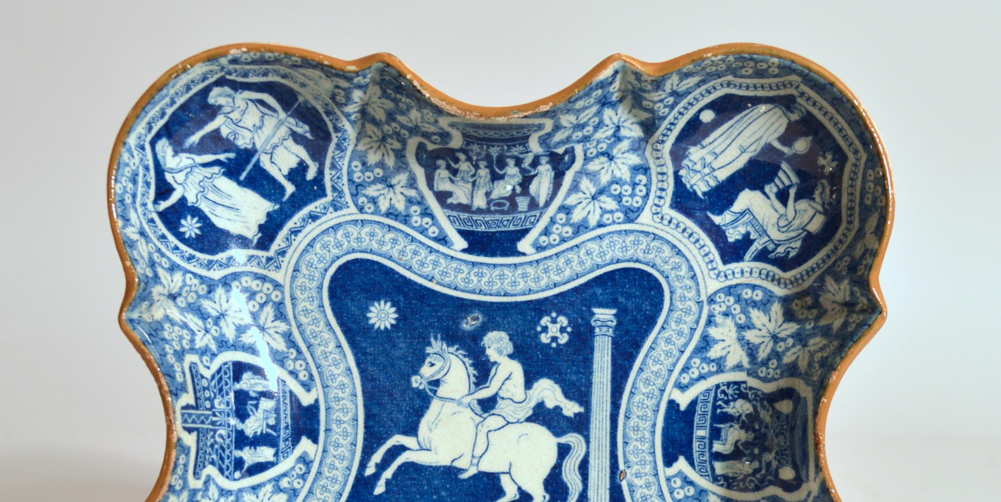 Spode Pottery neoclassical Greek Pattern Blue Dessert dish,
circa 1810

The Spode pearlware pottery-shaped dessert Greek Pattern dish has a central panel with a horseman on a rearing horse panels to the rim of urns and shaped panels with