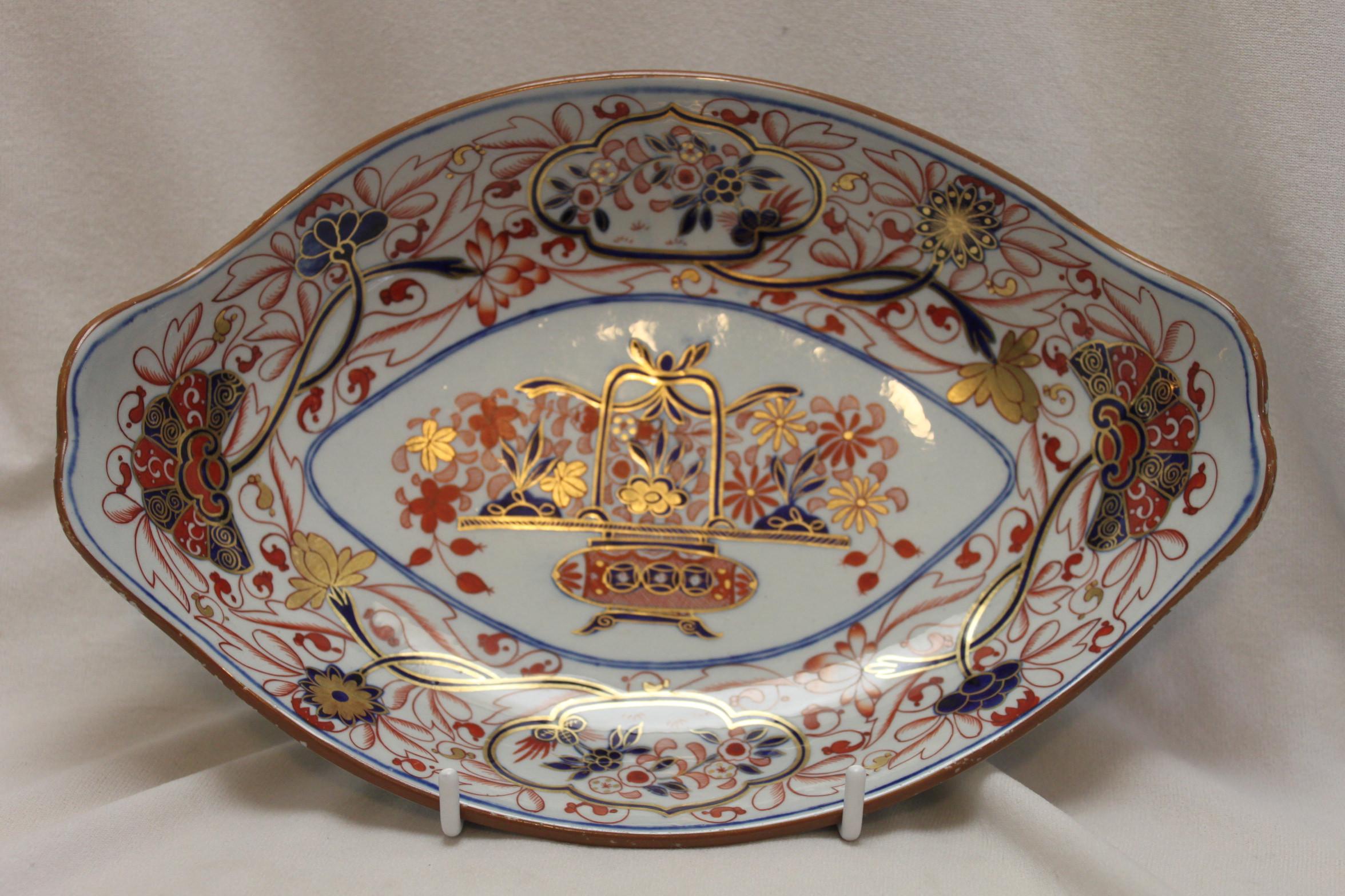 This oval hand coloured and gilded Spode Stone China dish is decorated with an Imari pattern- pattern 2283. It could also be that this item is a stand for a small tureen in the dinnerware or dessert range. The decoration is done in the typical Imari