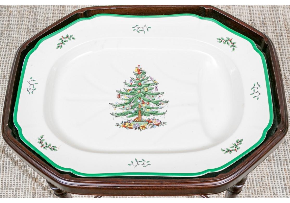 Un plat à viande ovale façonné avec puits dans le motif classique de l'arbre de Noël de Spode. Présenté sur un support en bois teinté foncé de forme complémentaire, avec des pieds tournés et un châssis en X. Le plateau est amovible.

Condit : Divers