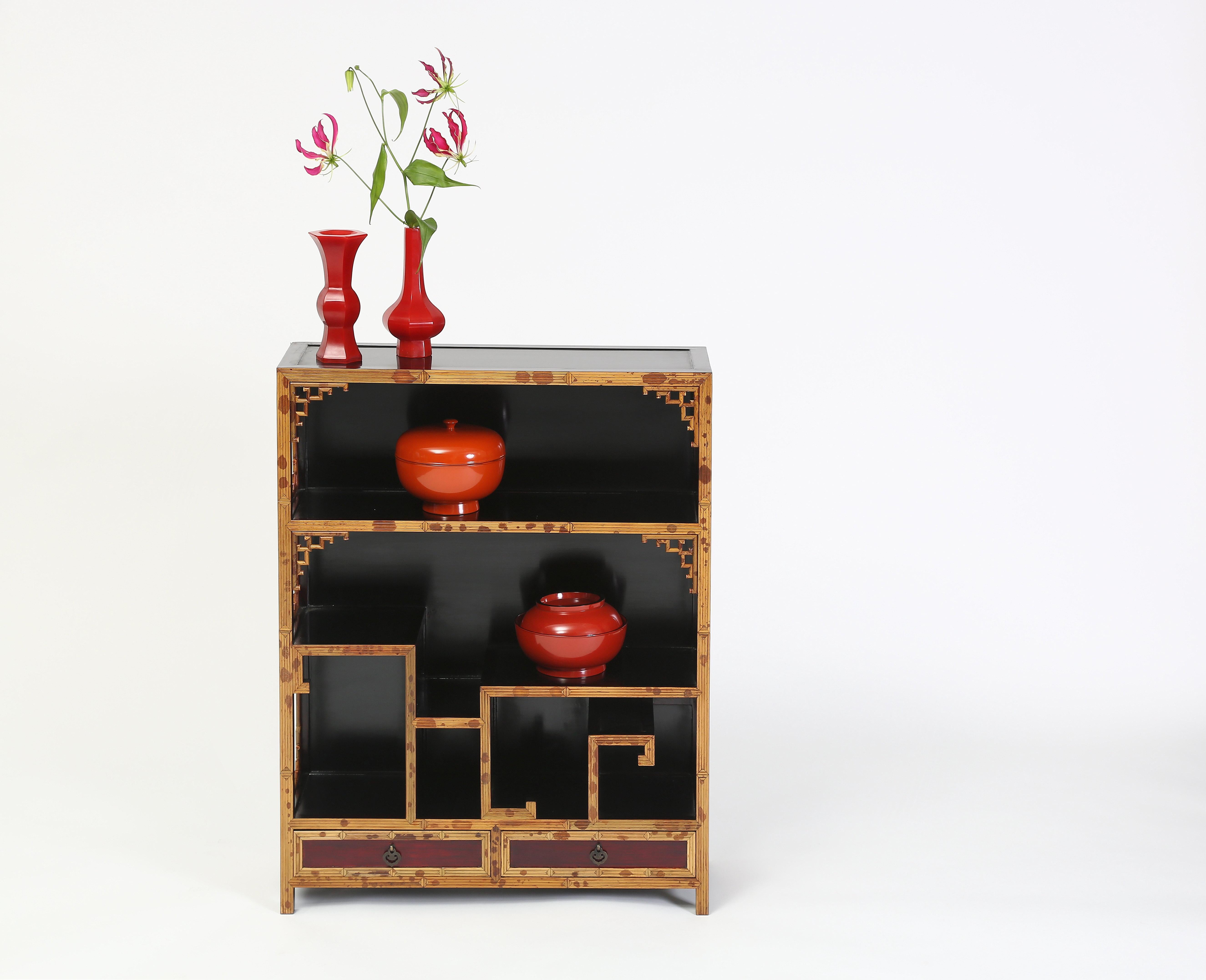The chinoiserie shelves cabinet handcrafted in spotted bamboo and black lacquered hard wood featuring curio shelves with a back atop a row of two bottom drawers is ideal for displaying objects of arts
Measures: 26