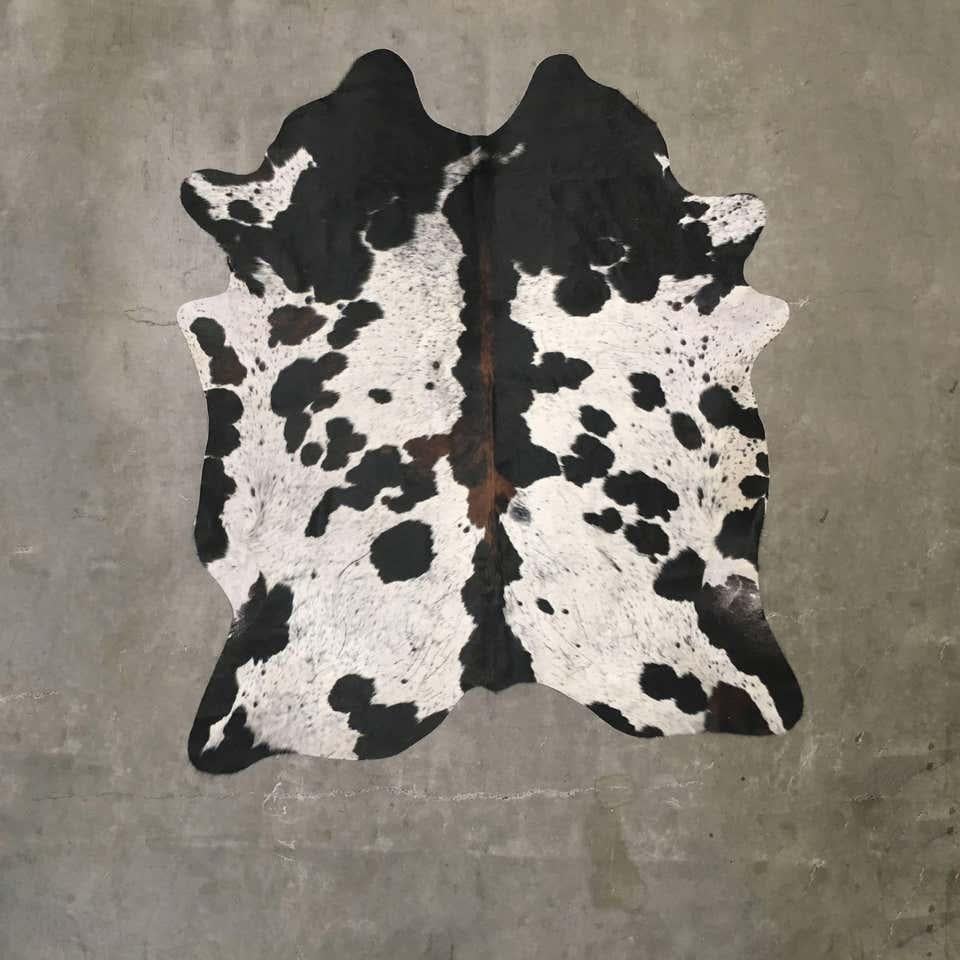 Natural cow hide rug, spotted tri-color with white, brown and black speckles.

Photograph depicts typical features of tri-color hides, and ordered hide rug will vary based on availability. Please inquire for images of individual available hides