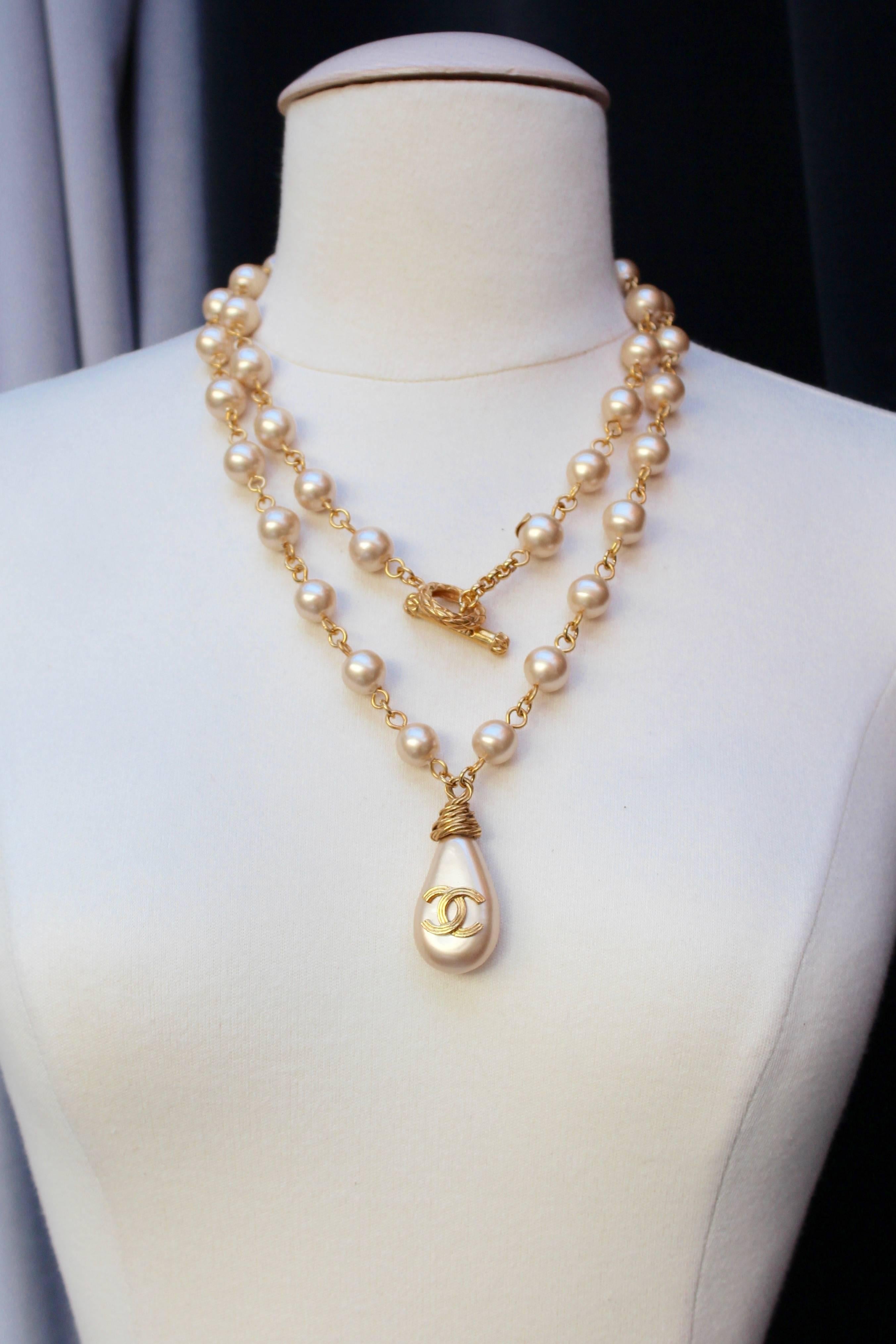CHANEL (Made in France) Long necklace composed of pearly beads on gilded metal thick wire. It is further decorated with a pearly “calisson” topped with a gilded metal CC logo. It can be worn in one or two strands.

Hinge clasp stamped with the brand