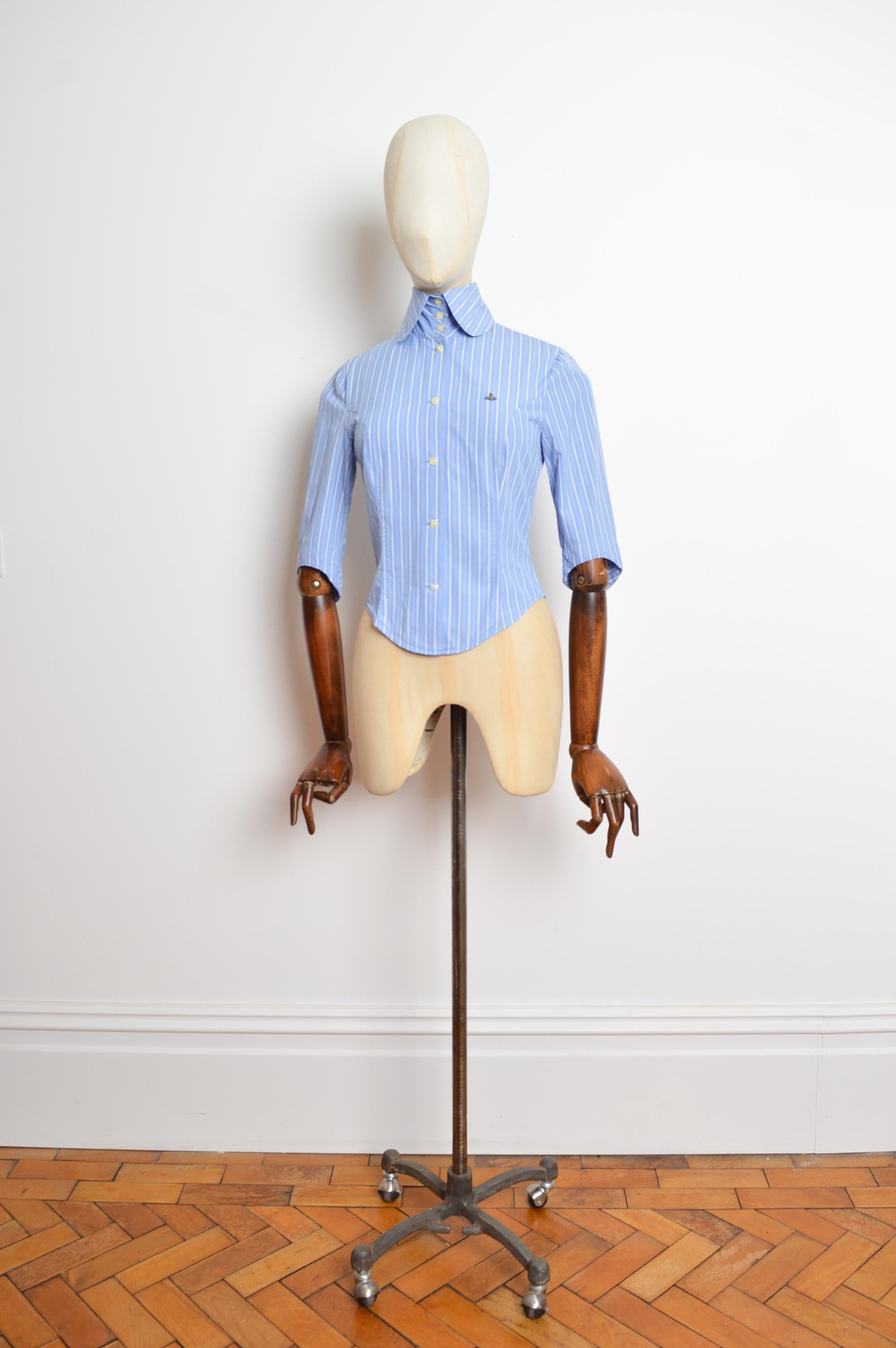 Une chemise iconique de Vivienne Westwood, ajustée, à rayures bleues et à manches 3/4, de la collection Printemps 1994. 
Taille ; Label 8 - Nous recommandons la taille UK 6.
Les mesures sont indiquées en pouces ('')
De la fosse à la fosse ; 17
