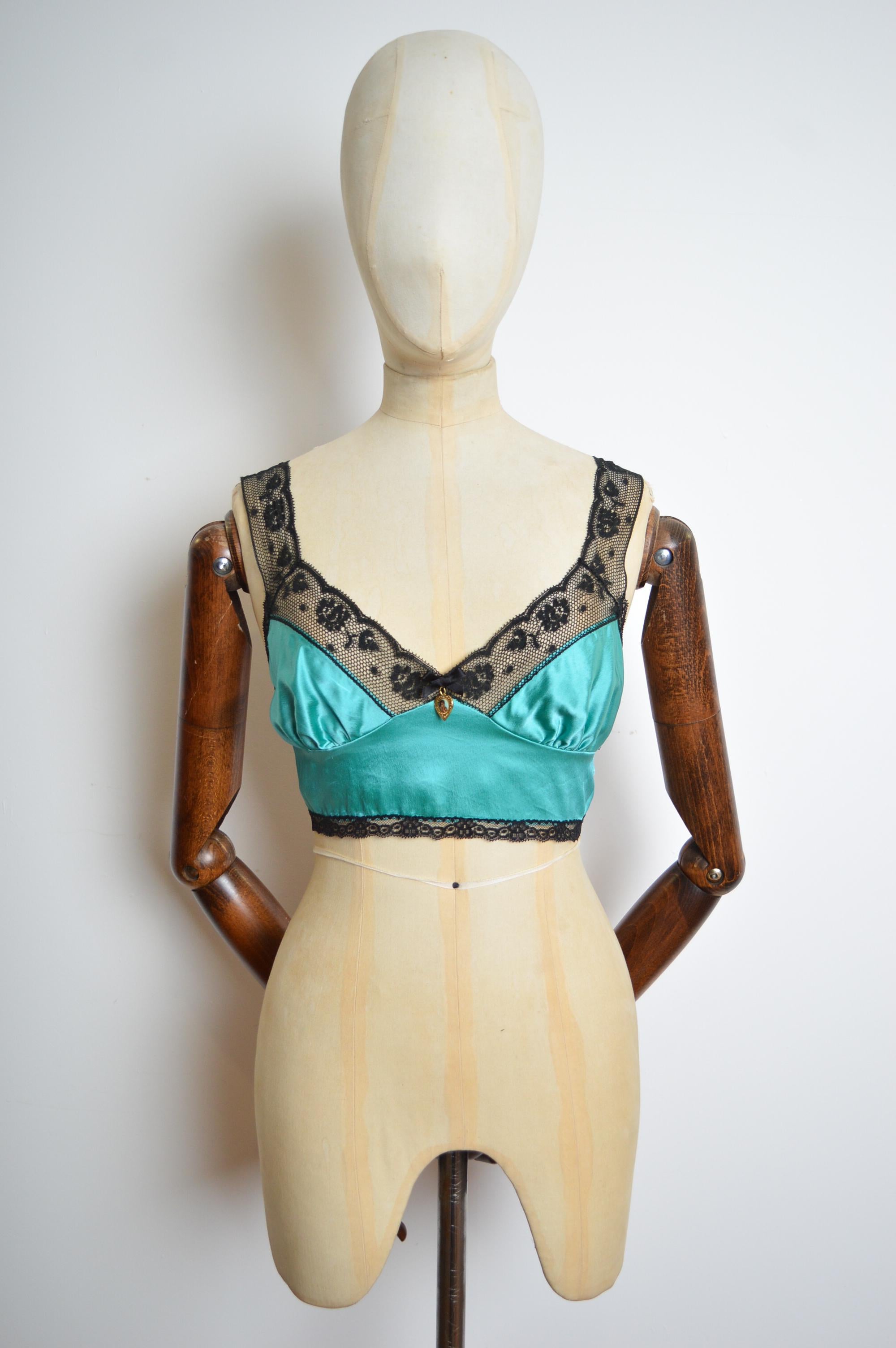 A rare and Beautiful ornate Spring / Summer 1995 Turquoise Satin & Black Lace Bralet by Dolce & Gabbana. (As worn by Monica Bellucci and Carla Bruni on the Runway) Featuring decorative cherub charm, gently elasticated reverse and fine black lace