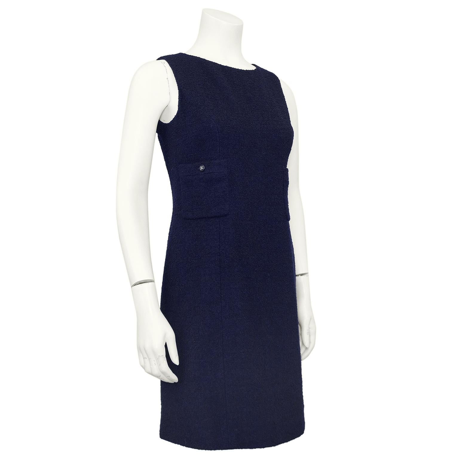 Classico e sempre elegante abito Chanel in lana blu navy della collezione primavera 1996. Senza maniche, con scollo alto a barchetta, cucitura centrale e tasche applicate con bottoni neri e argento con logo cc a incastro. Cerniera invisibile al