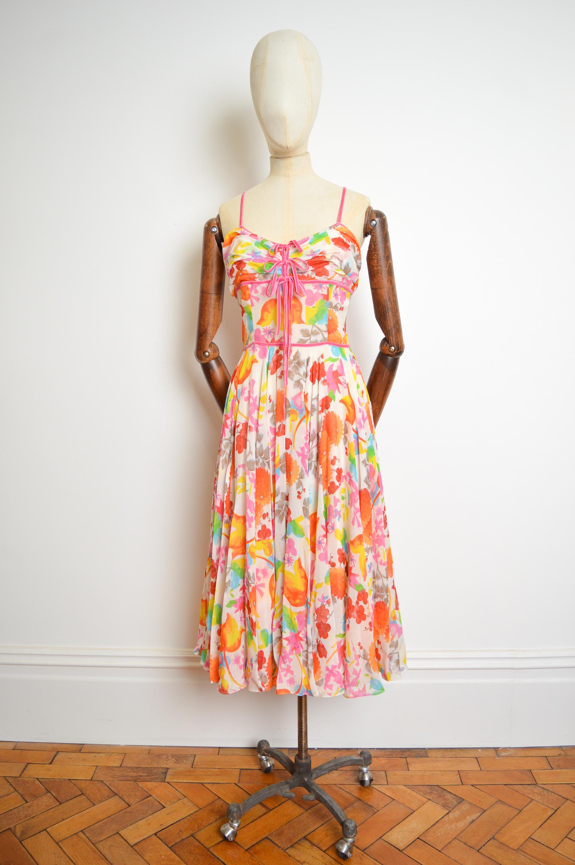 A rare, Iconic Christian Dior Spring 2006 chiffon layered silk Dress designed by John Galliano crafted from a beautiful floral crepe material with delicate velvet bow details adorning the front.

Measurements are provided in Inches.   
Top of