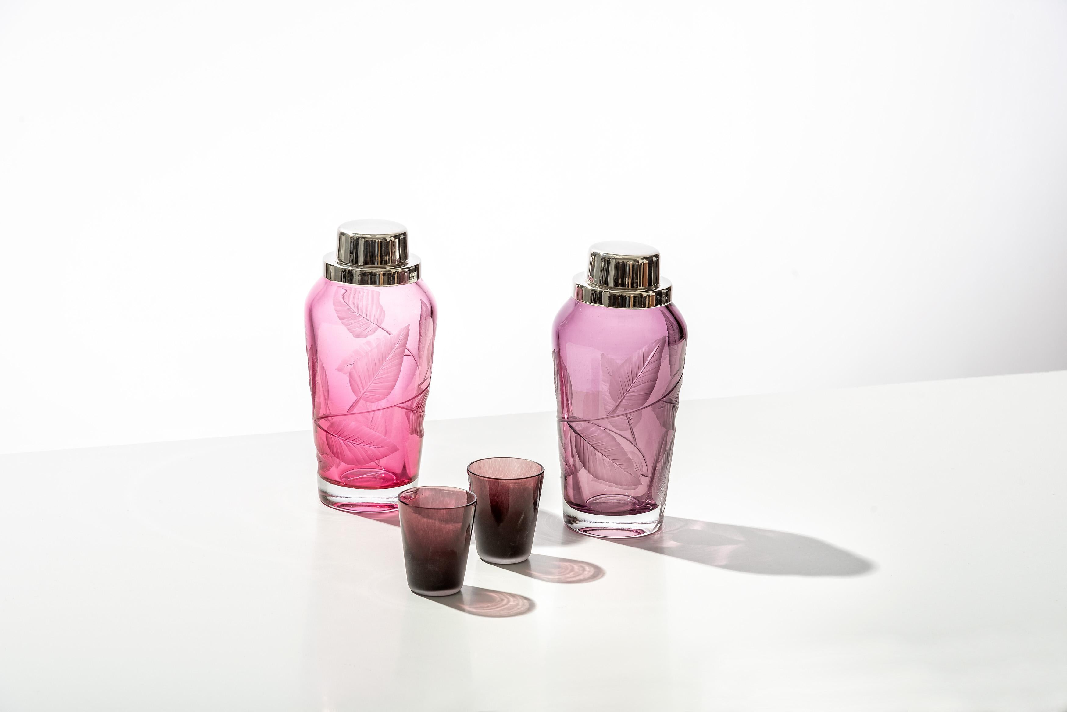 Questo shaker in vetro soffiato e intagliato a mano trae ispirazione dalla natura. Questo shaker da cocktail è decorato con intagli di foglie di edera primaverile e viene fornito con un coperchio argentato montato e un colino incorporato per un uso