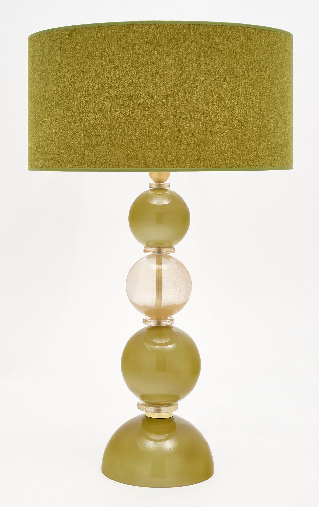 Pair of spring green Murano glass lamps featuring hand-blown glass spheres in spring green and light gold. We love the green linen shades and strong impression of this pair. They have been newly wired to fit US standards.
