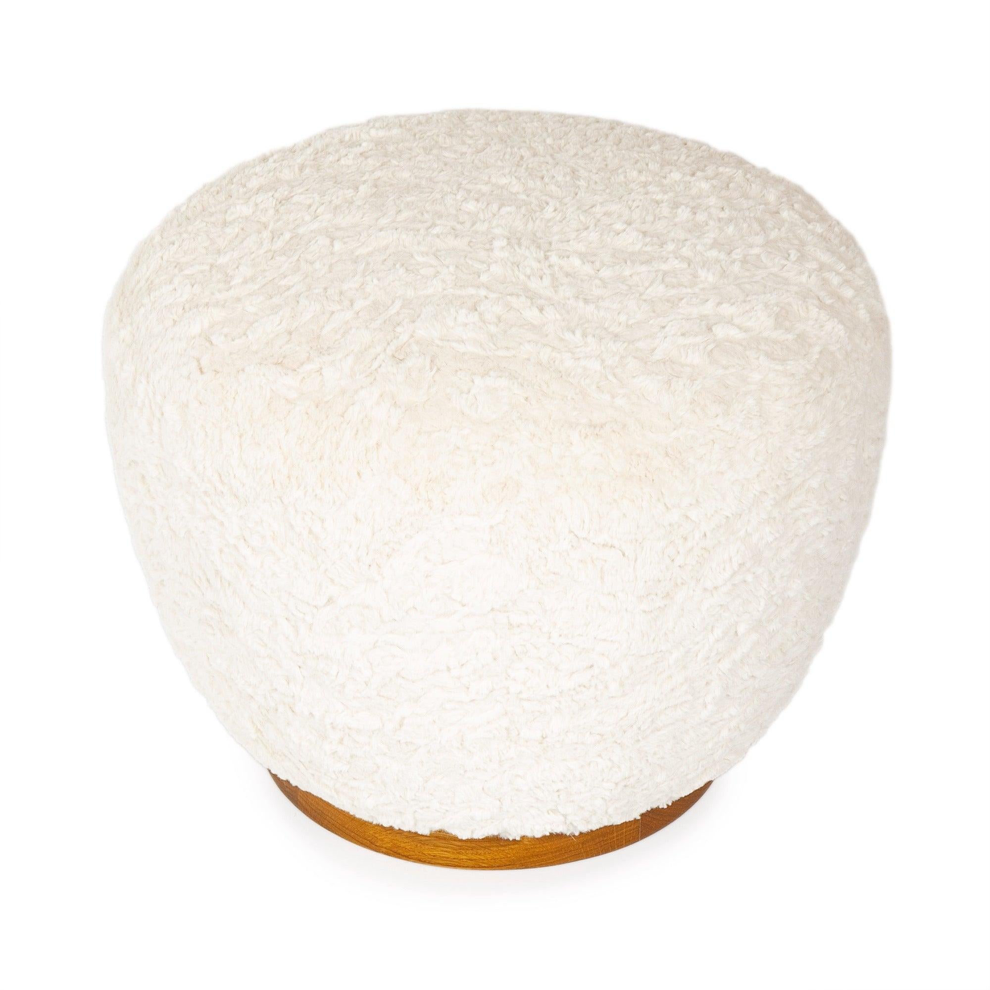 A traditional hand crafted and tied coil spring pouf ottoman with an oiled walnut base in faux shearling. this item requires upholstery.