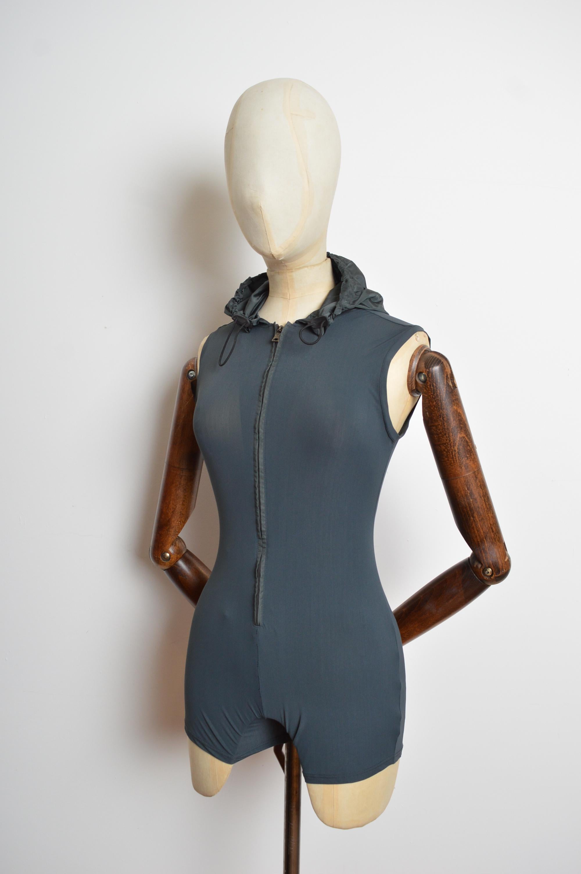 Spring / Summer 1999 PRADA Grey Technical fabric Hooded Zipper Playsuit - 2000’s Romper 
Spring / Summer 1999 PRADA Grey Technical fabric Hooded Zipper Playsuit crafted from a stretchy Nylon fabric with adjustable draw tie Hood and iconic PRADA