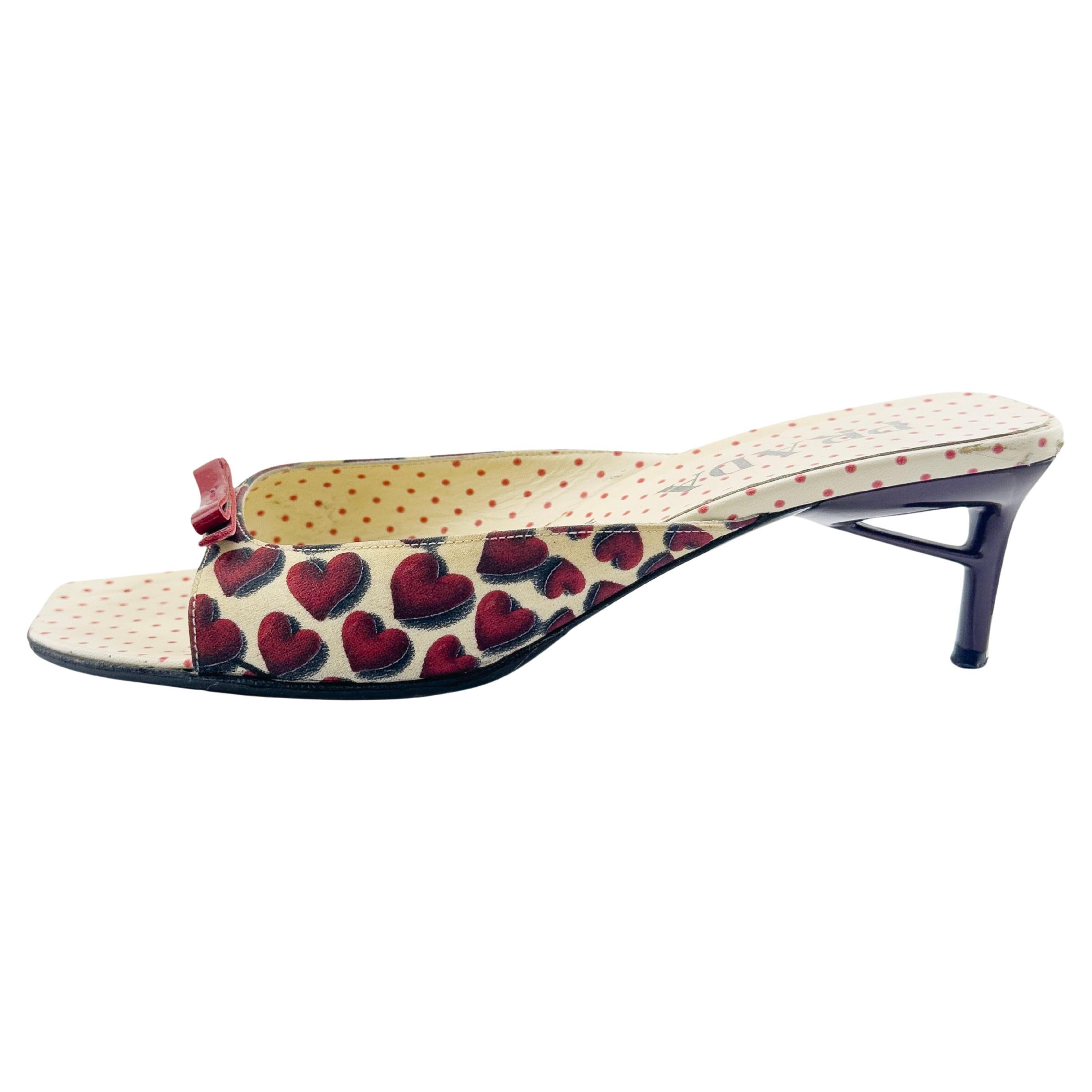 Prada kitten heel mules from the iconic Spring/Summer 2000 collection. Red, black and white heart print silk exterior with cream and red polka dot leather interior. Small red patent leather flat bow details and black heels and soles. Good vintage
