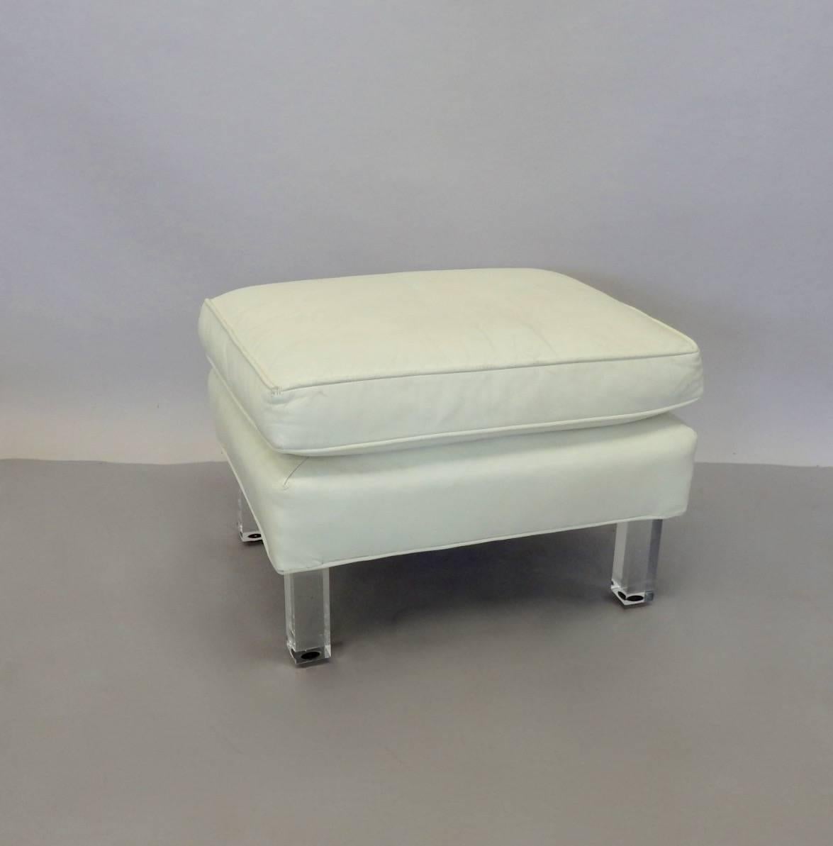 High style white leather ottoman on Lucite legs. Very well made. Leather shows patina more than age. Wrinkles in the original finish. Lucite also shows checking in the certain light.