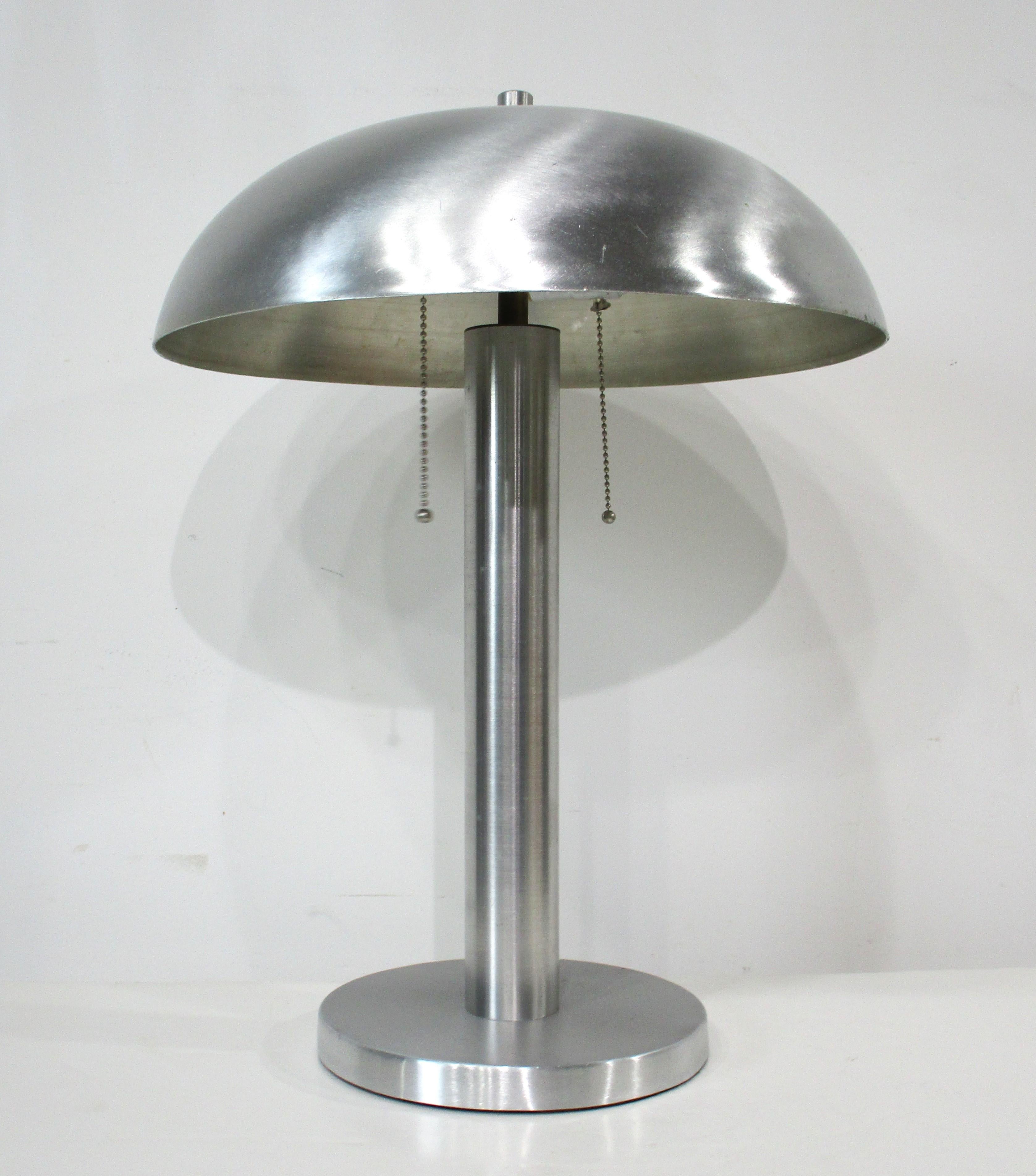 A spun aluminum Art Deco lamp with matching spun aluminum domed shade on a round base with felt to the bottom to protect your table . Having a double socket will give the area you use it in plenty of light with on and off chain pull switch  .