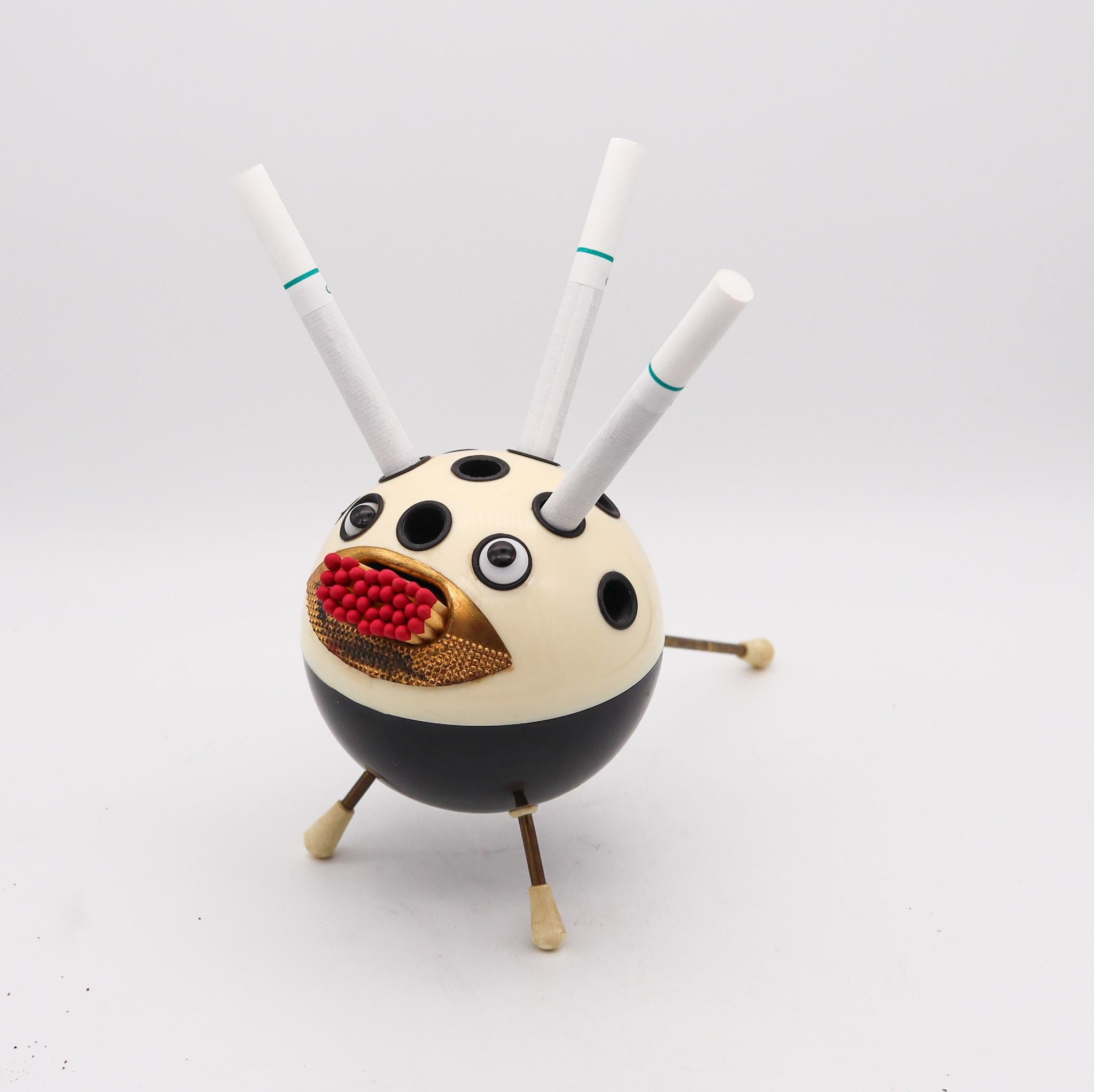 Sputnik space era cigarette holder.

Extremely funny and very hilarious piece, created during the space era back in the 1950s. Crafted in the shape of a Sputnik in black and cream plastics with three steel legs. The so called globe fish have ten