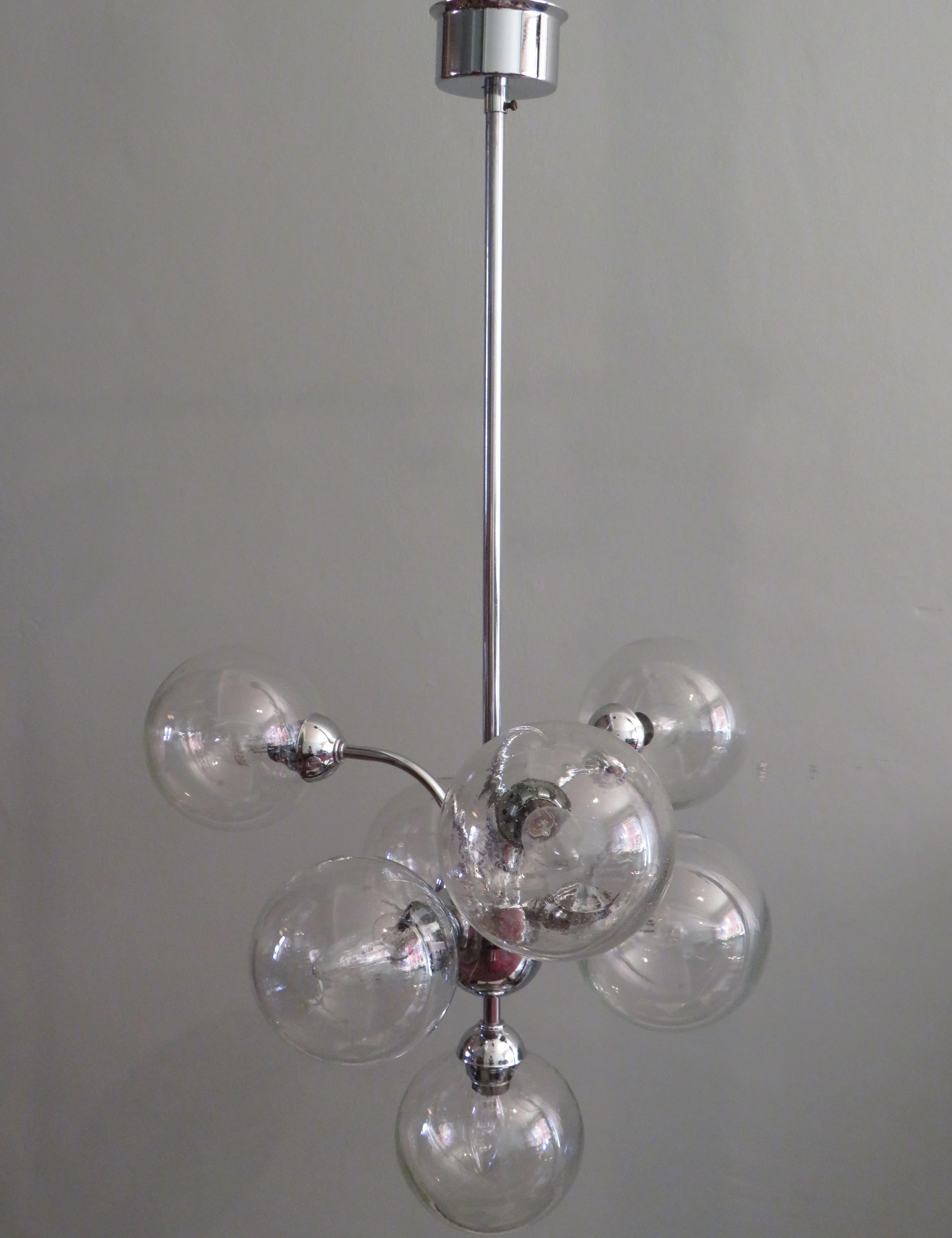 This chromed chandelier, manufactured by Massive in Belgium in the 70s has 7 spheres of transparent, air bubbles glass.
The height of the chandelier is 87 cm and he has a circumference of 45 cm.
The spheres have a diameter of 15 cm and has a E 14
