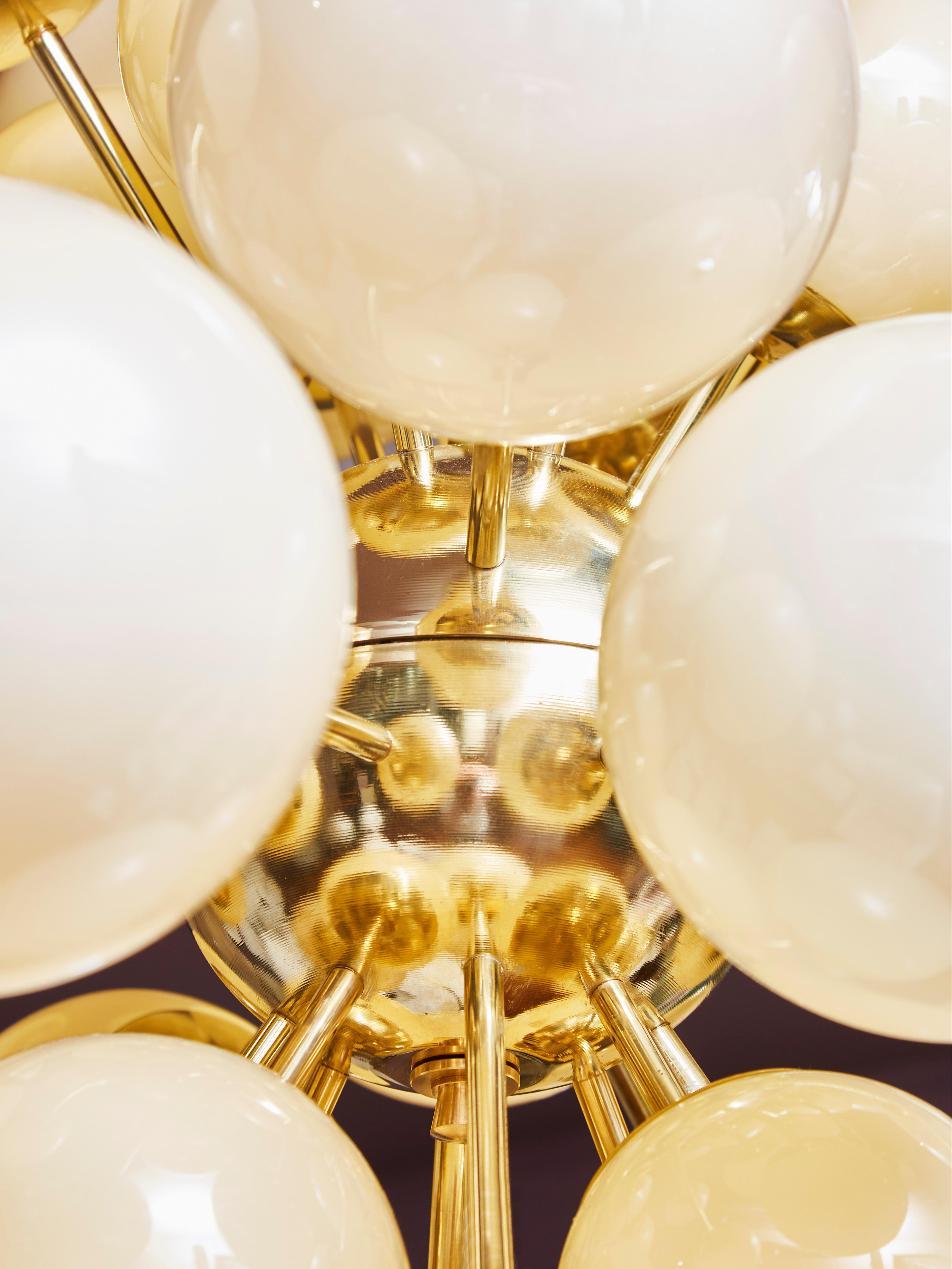 Elégant lustre Sputnik avec des globes en verre opalin éclairés et de différentes tailles, provenant de Murano. Structure en laiton. Piqûres de diamant Miroir.
Création par le Studio Glustin.
 