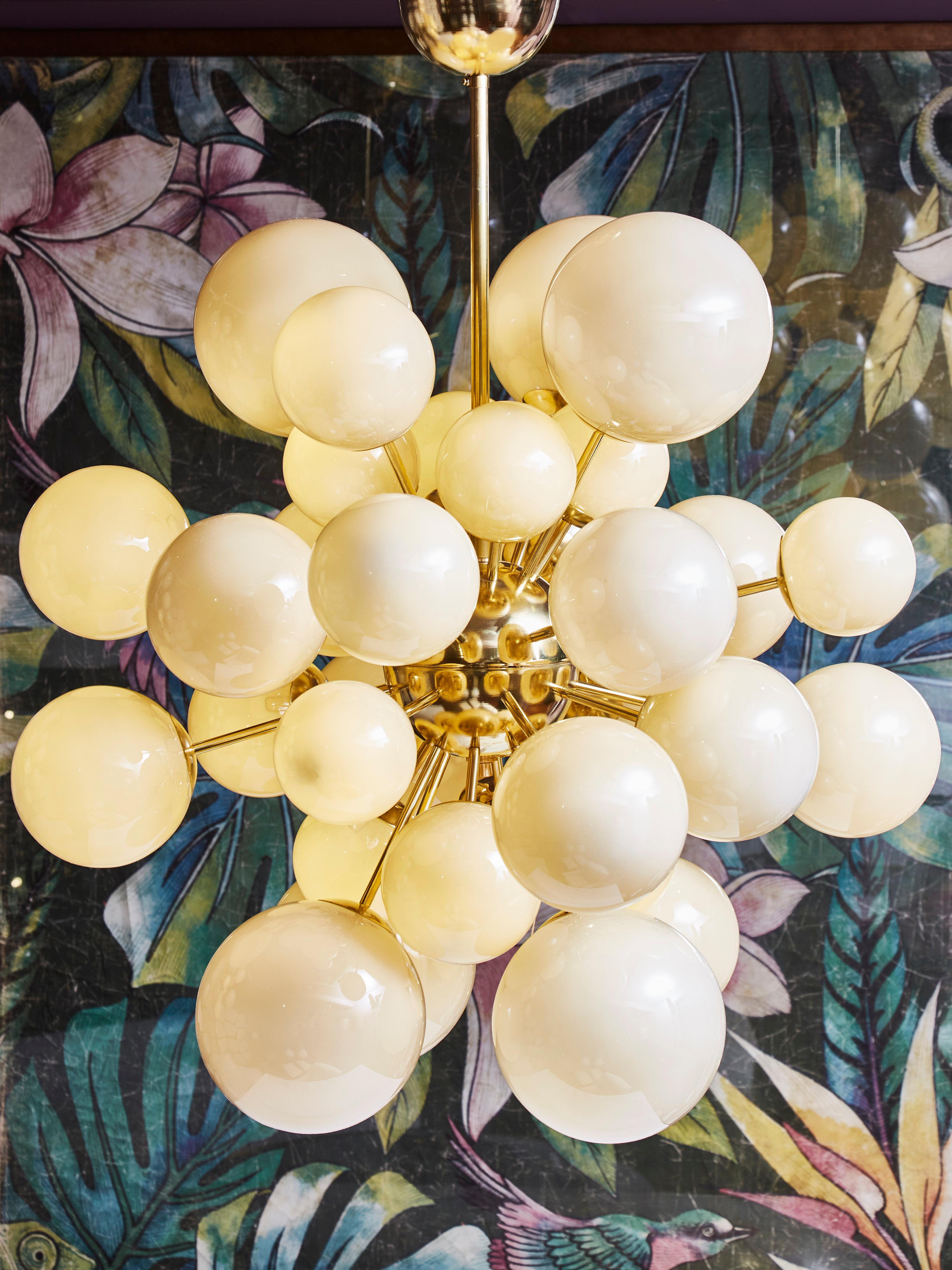 Elegant Sputnik chandelier with enlightened and different sized opaline glass globes, from Murano. Structure in brass. 
Creation by Studio Glustin.
Pair available.