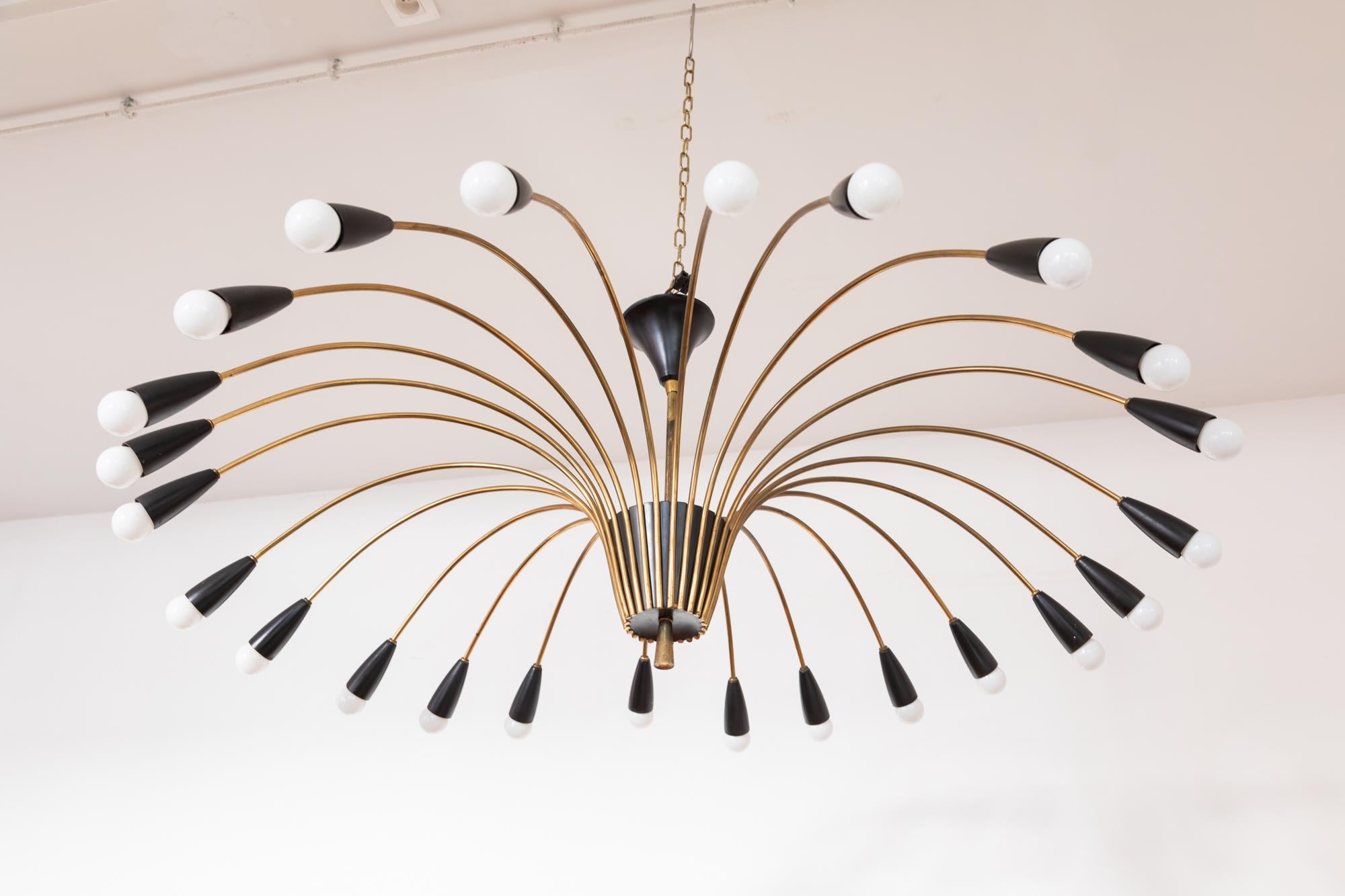 Midcentury chandelier flush mount featuring a sunray of elegant brass arms with contrasting black enamel. 24 bulbs.
Designed by Kaiser Germany. Mint condition. Dimension: 110 W x 45 H x 110 D cm.