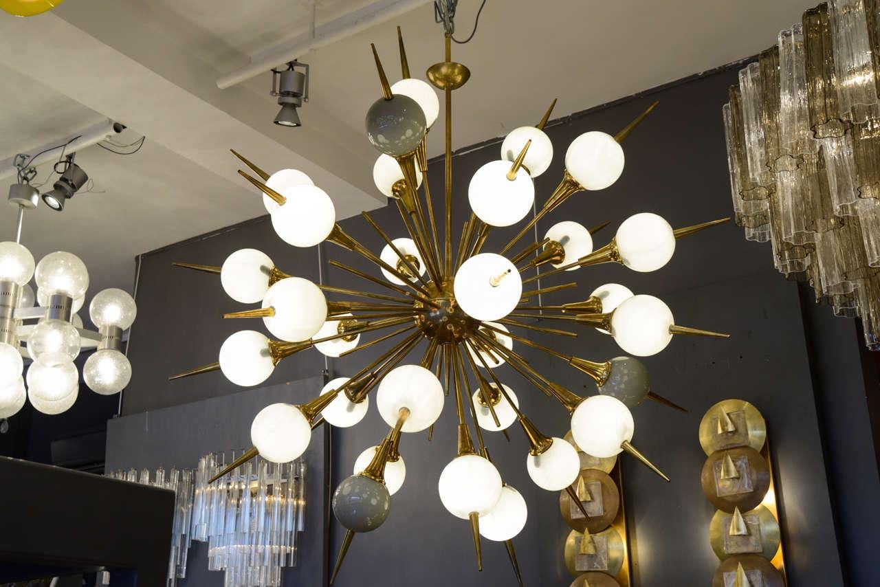 Large Sputnik style chandelier made of unlacquered brass, thirty arms of light with grey tinted globes diffusers.