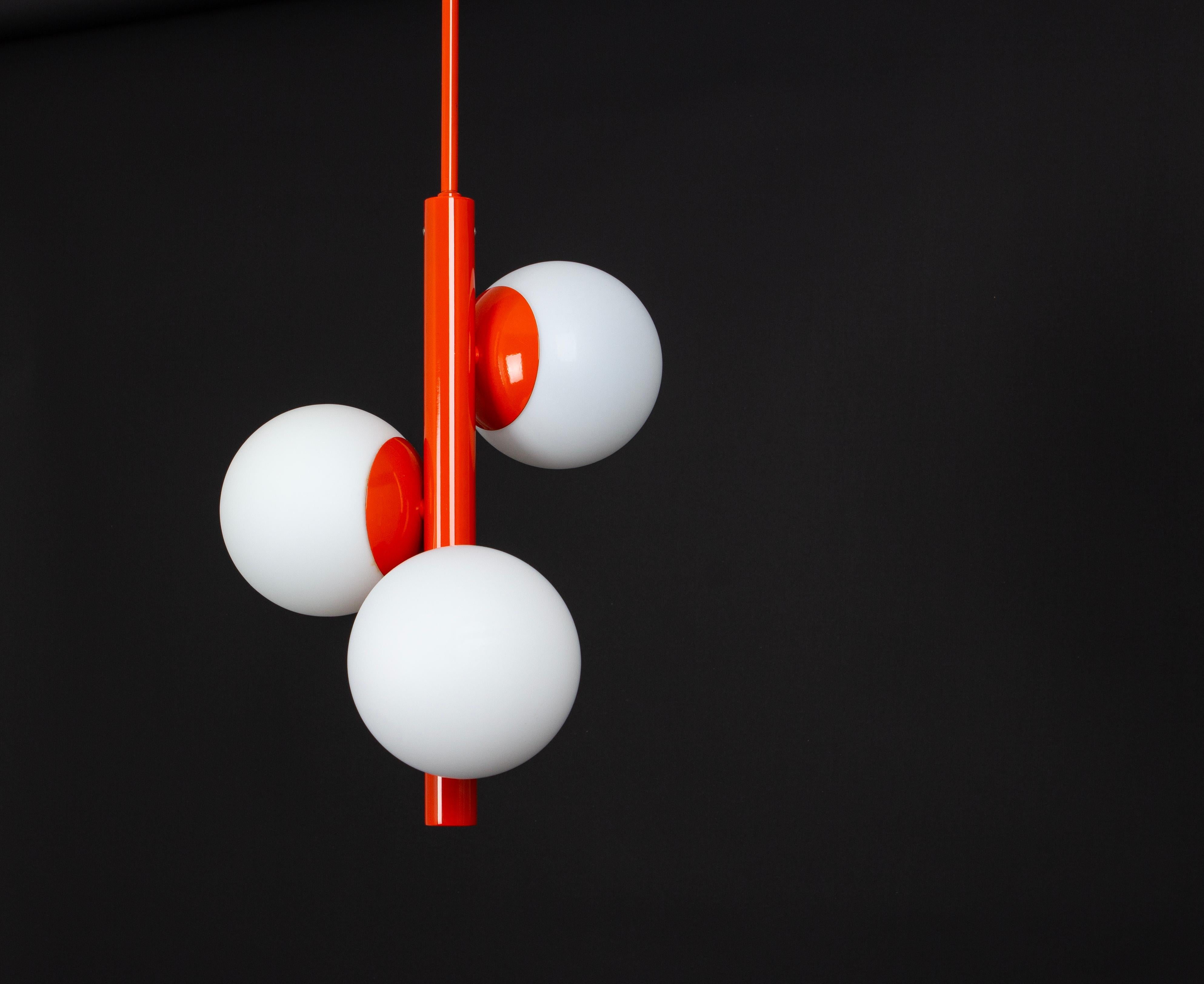 Merveilleuse lampe suspendue Sputnik fabriquée par Kaiser Leuchten, Allemagne, vers 1970-1979.
Grand lustre en forme d'Atomium avec 3 pièces en verre opale.
Ce luminaire exquis arbore une couleur orange captivante qui ajoute une touche de