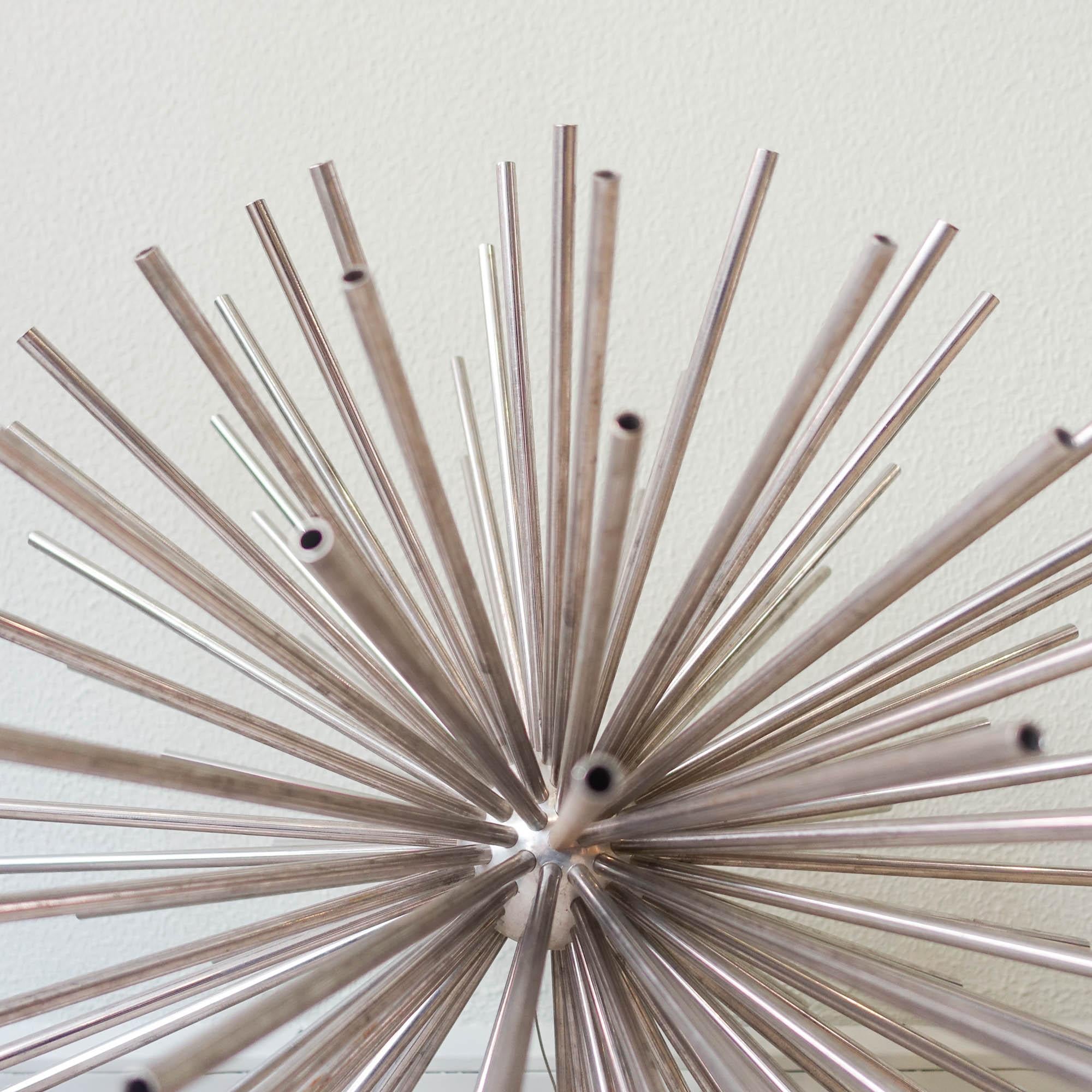 This sputnik sculpture was designed by Curtis Jere, in USA, during the 1960s. It is made of metal and nickel plated with a sunburst shaped pattern. Curtis Jeré was the shared pseudonym of two artists, Curtis Freiler and Jerry Fels, who used enamel,