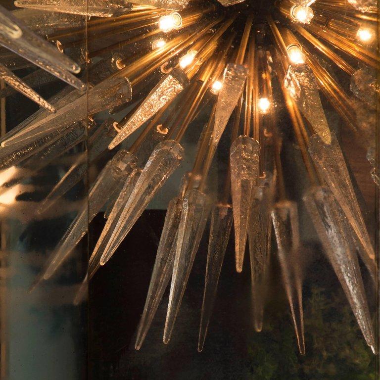 Sputnik shard chandelier comprising of 127 Murano glass shards with natural, un-lacquered brass rods and fixed to a central black orb. Light bulbs are fixed to the central orb, giving a central glow of light. 

Wired for EU this chandelier