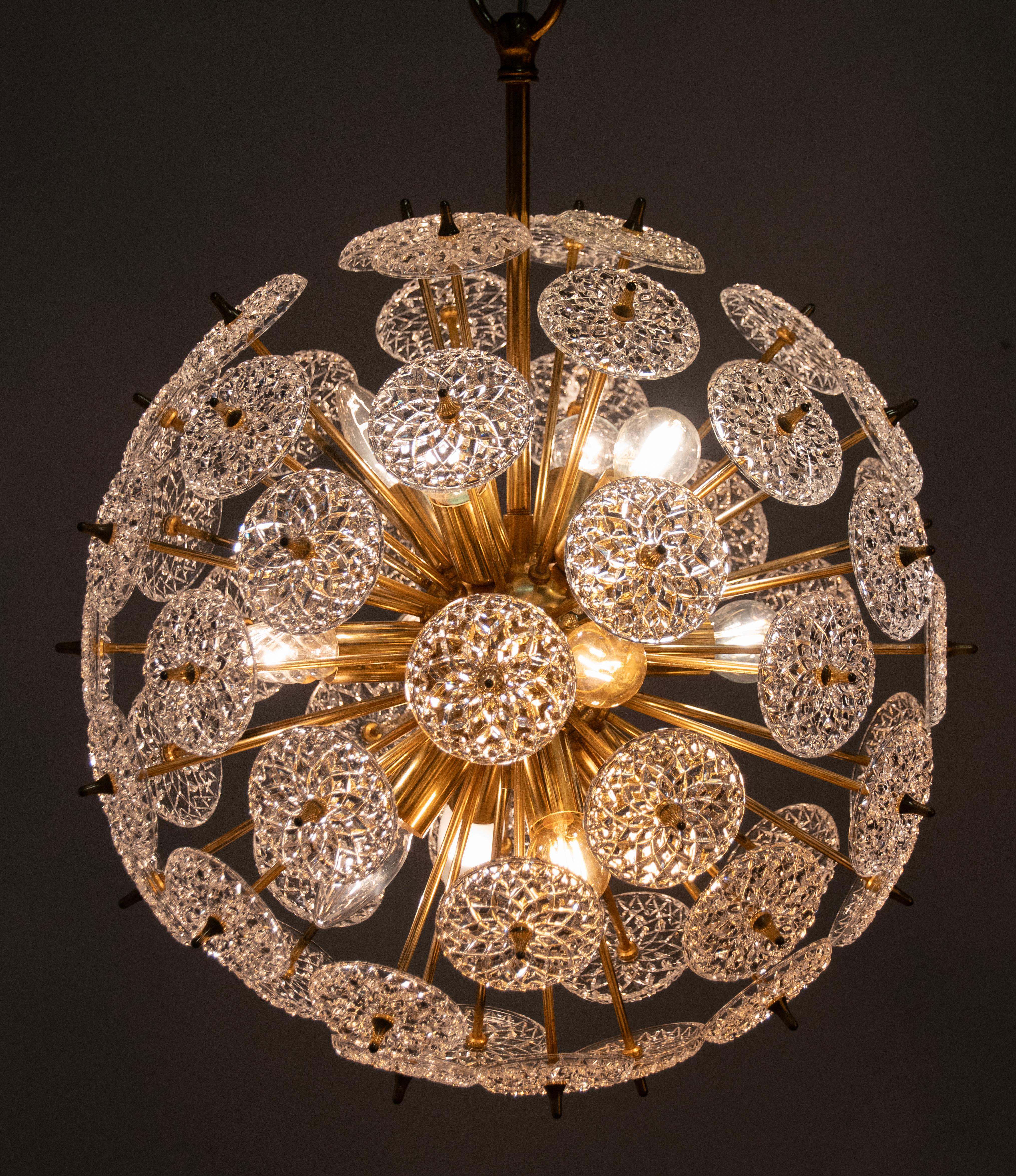 Beautiful ceiling lamp, a Sputnik model with many glass disks. The disks are cut and therefore you see a nice reflection of the light shining through this lamp. The interior is made of polished brass colored metal with twelve E14 lamp sockets. This
