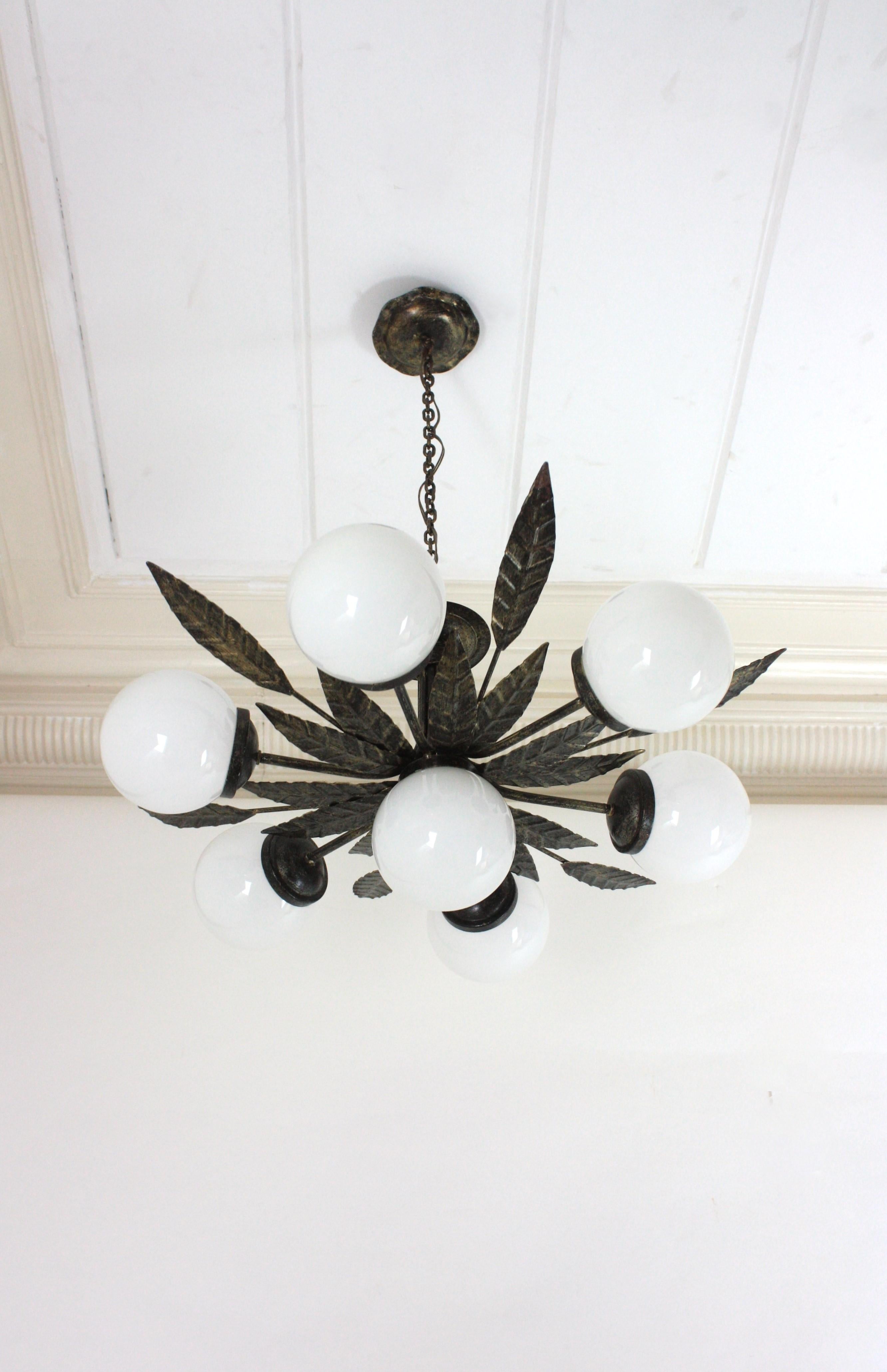 Lampadario a raggiera con 7 globi di vetro al latte, ferro argentato e dorato
Eccezionale lampadario a globo in vetro Sputnik / plafoniera a incasso in ferro patinato.
Prodotto da Ferro Art, Spagna, anni '50.
Questo lampadario a sette luci è