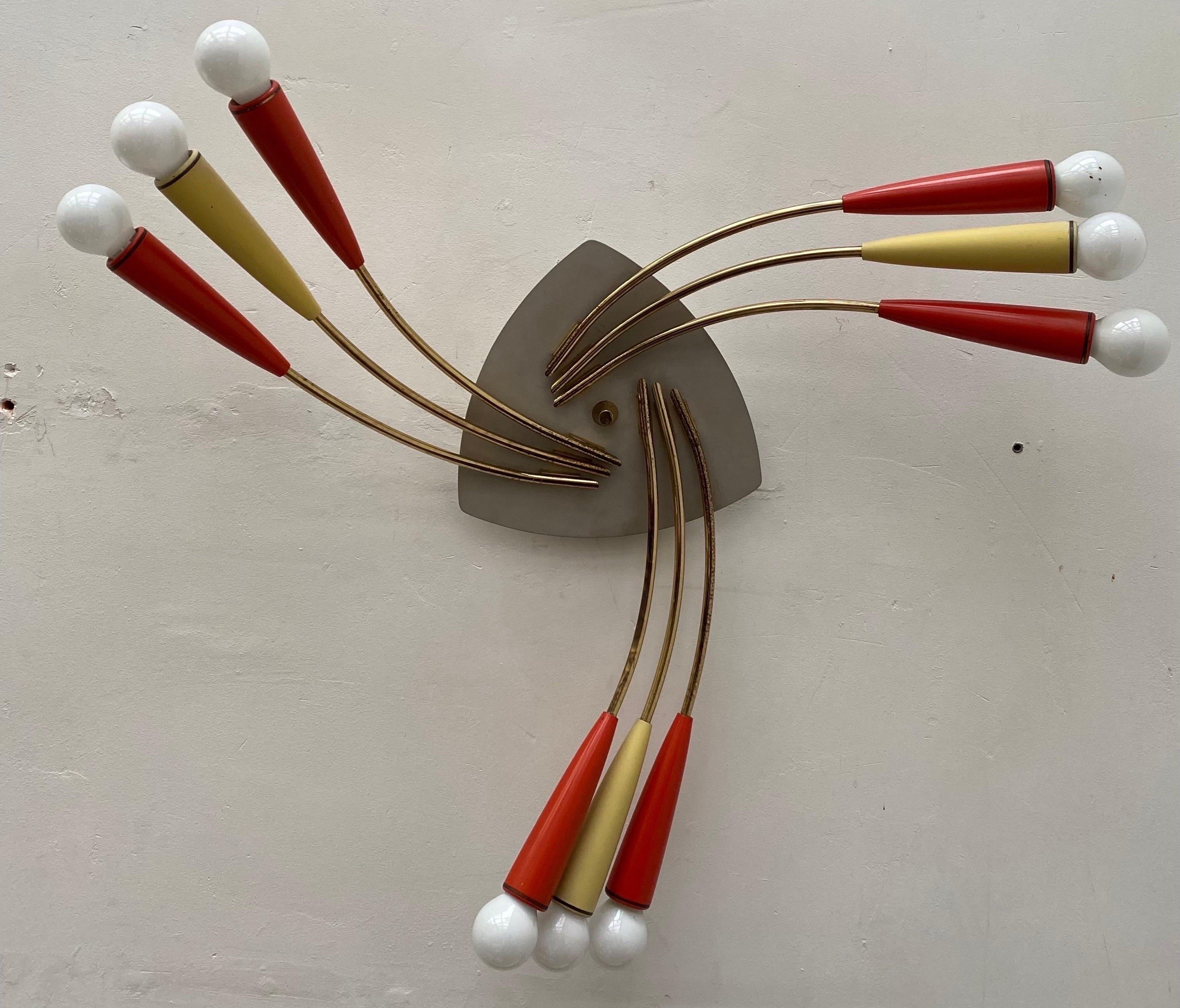 Large circle Sputnik flush mount or wall lamp from the 1950s. In Stilnovo style three large interlocking brass stems with three lacquered cones. The colorful red and yellow cones 9 sockets for original E14 sockets.
The sputnik can be mounted or