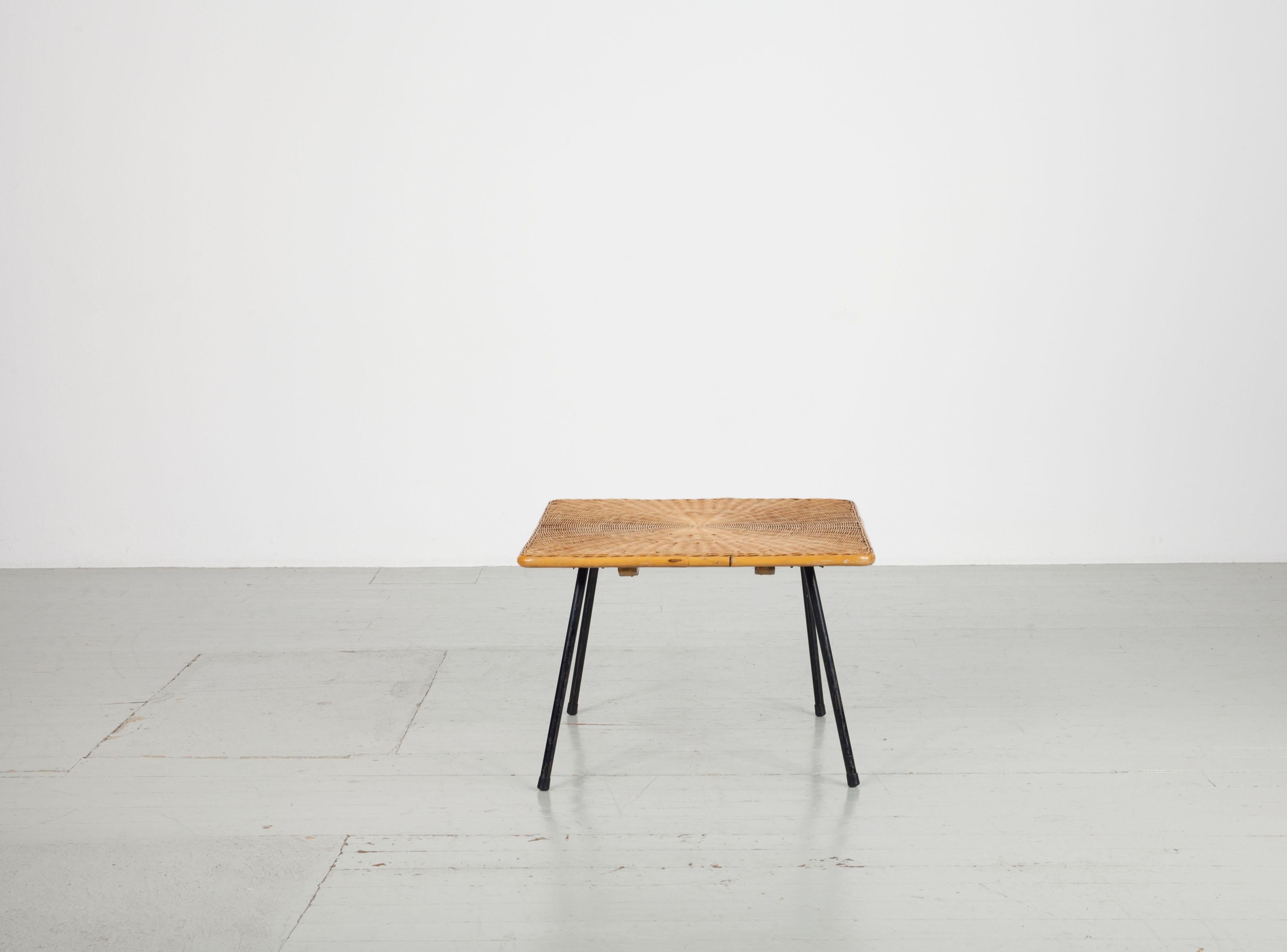 Quadratischer Sofatisch aus Korbgeflecht aus den 1950er Jahren mit 4 schwarz lackierten Metallbeinen. Das Flechtwerk liegt auf einer Holzkonstruktion und macht den Tisch sehr stabil. Die Umrandung ist aus Bambus gefertigt. Die Beine können