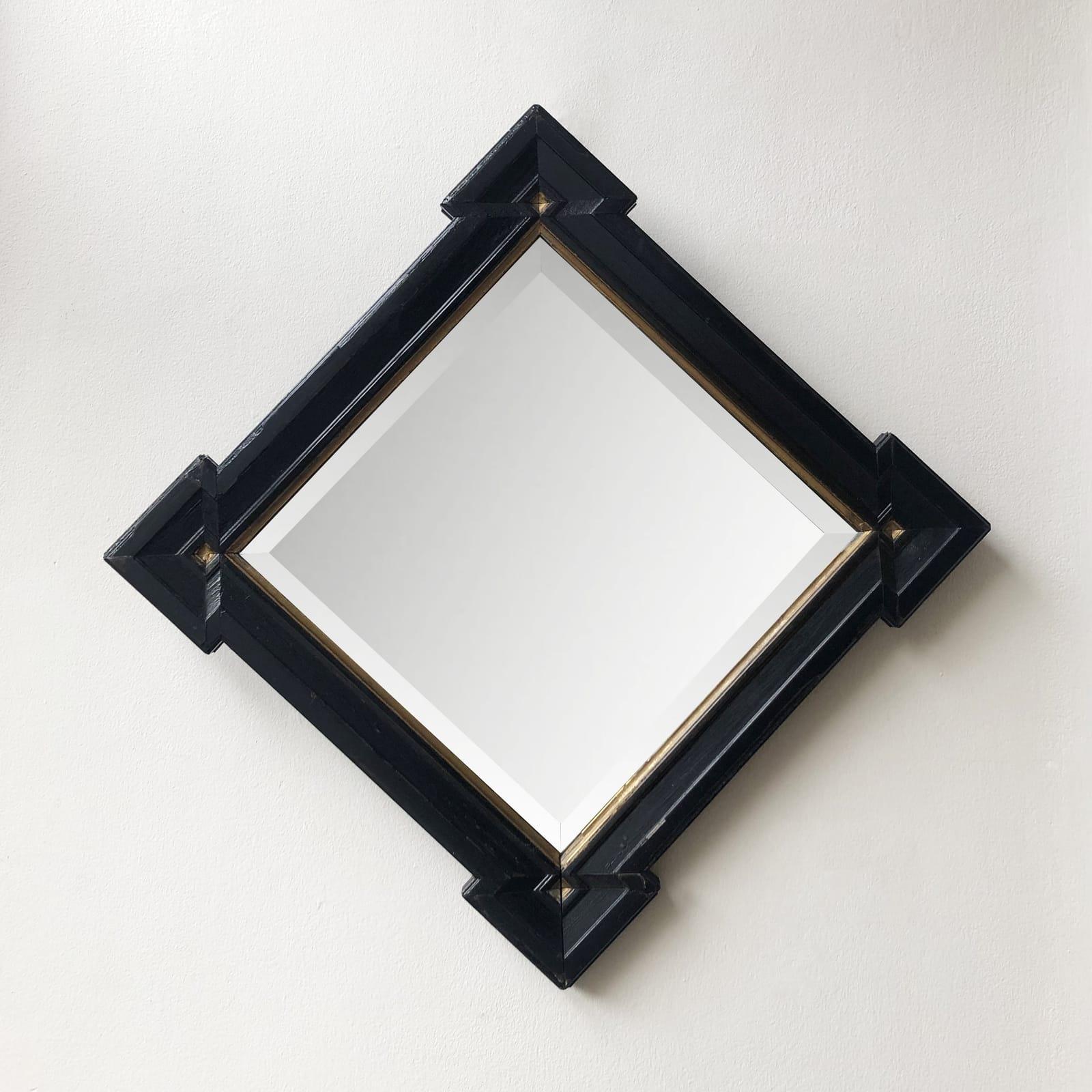 English turn-of-the-century square wall mirror with ebonized frame and gilt detailing. A wonderful example of the Aesthetic movement's design principles in application. With its simple, geometric shape and clear commitment to craftsmanship, the